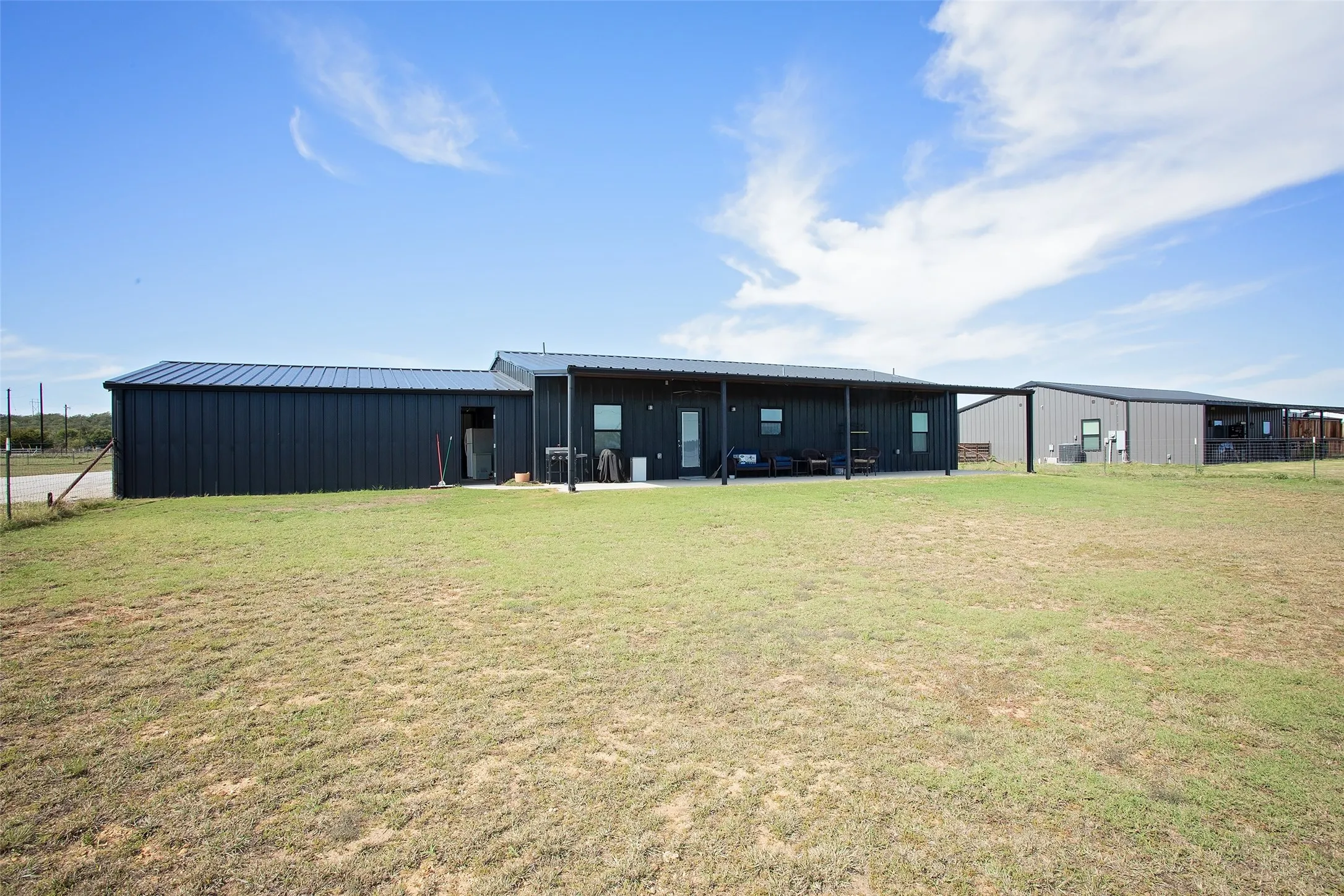 Black metal exterior siding, metal roof, and an expansive covered concrete patio