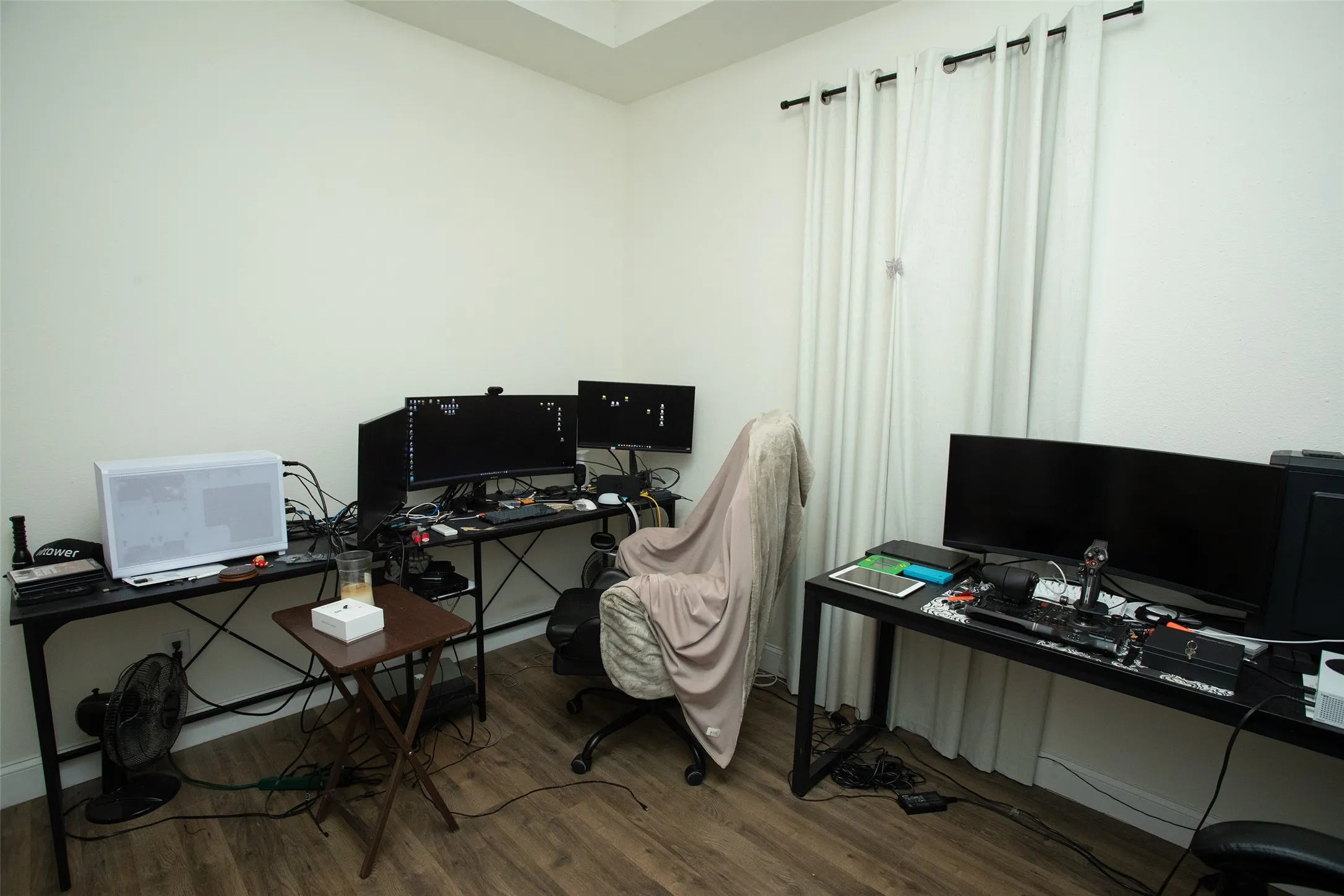 Room featuring wood-finish flooring, neutral wall tones, a tray ceiling, and full-length window drapery