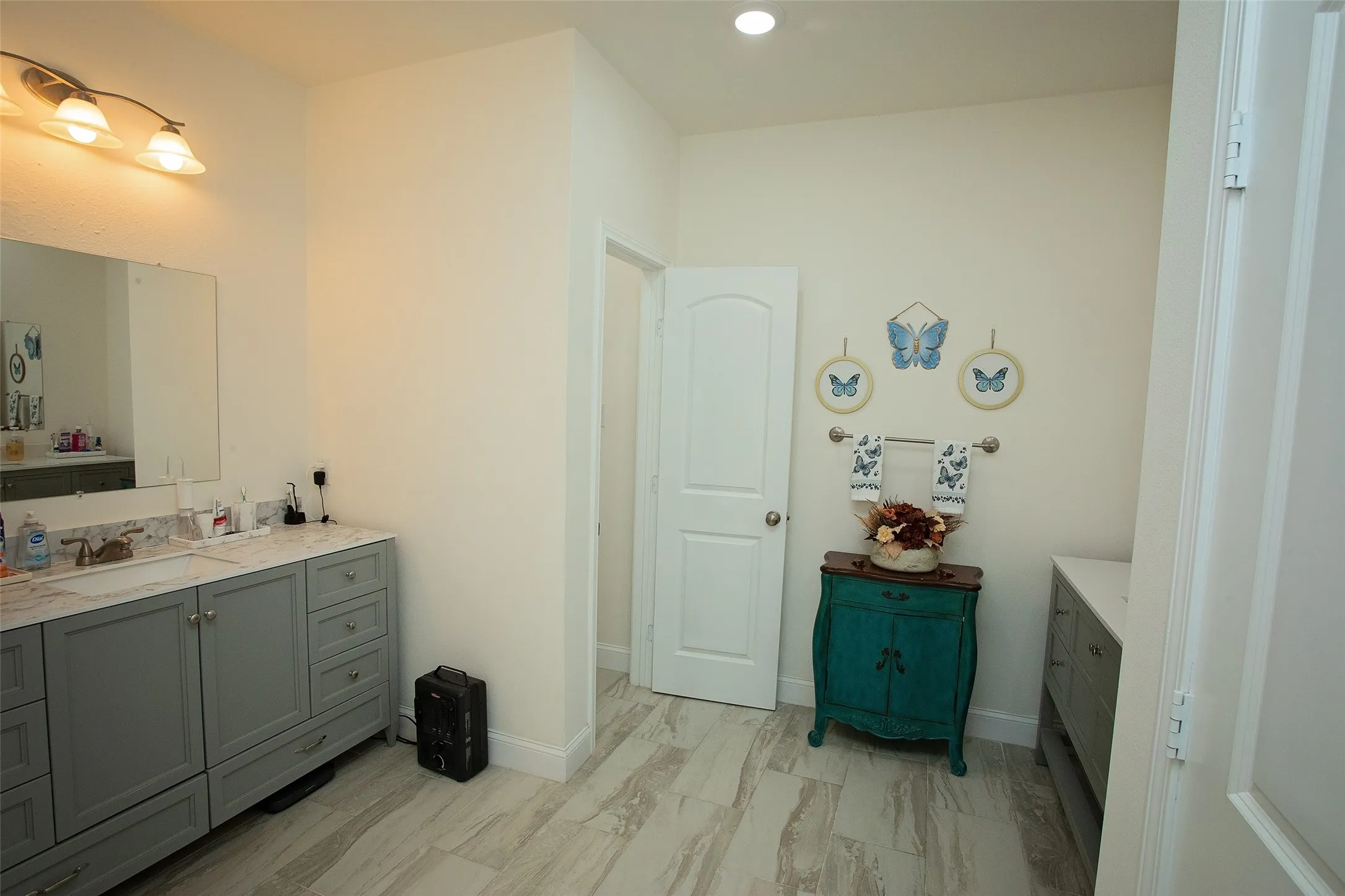 Dual gray vanities with stone countertops, integrated rectangular sinks, recessed lighting, and wood-finish tile flooring