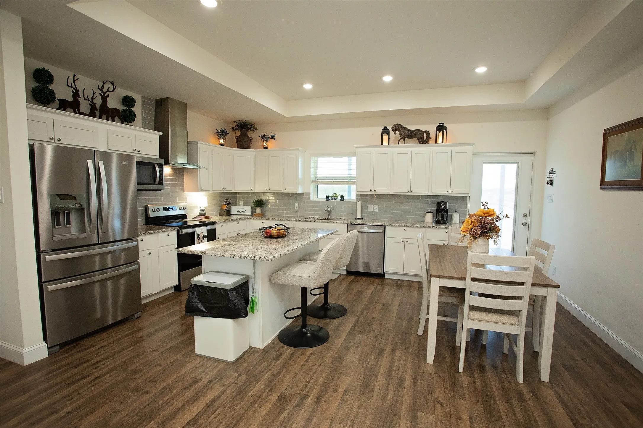 Kitchen featuring white cabinetry, stone-surface countertops, wood-finish flooring, a stainless steel kitchen island, and recessed ceiling lighting