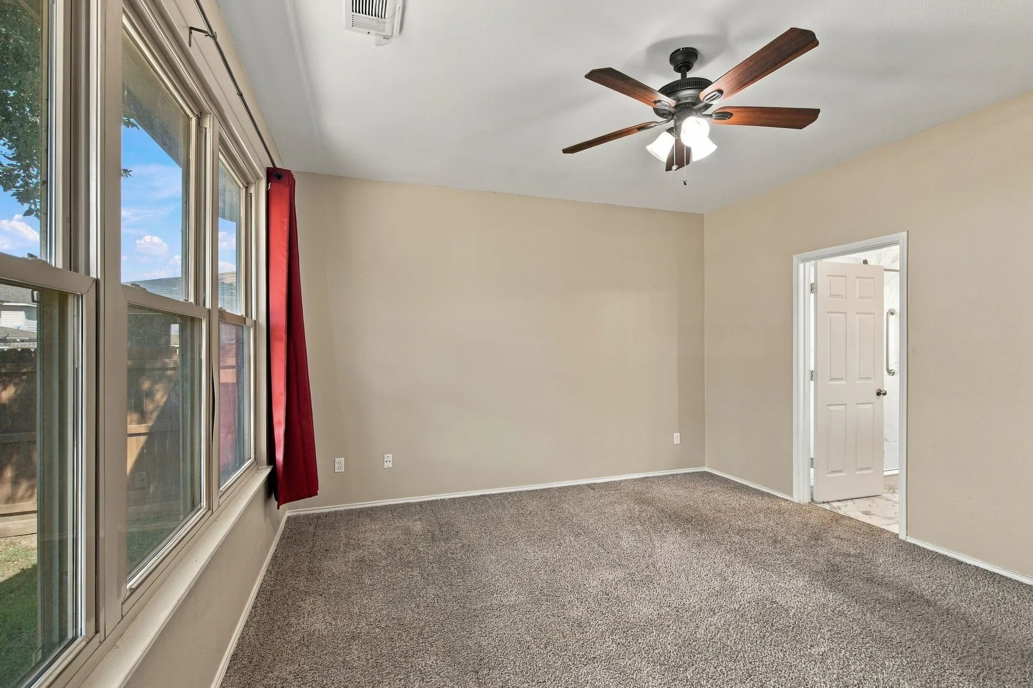 Spacious room featuring carpeting, large multi-pane windows, and a ceiling fan with integrated lighting