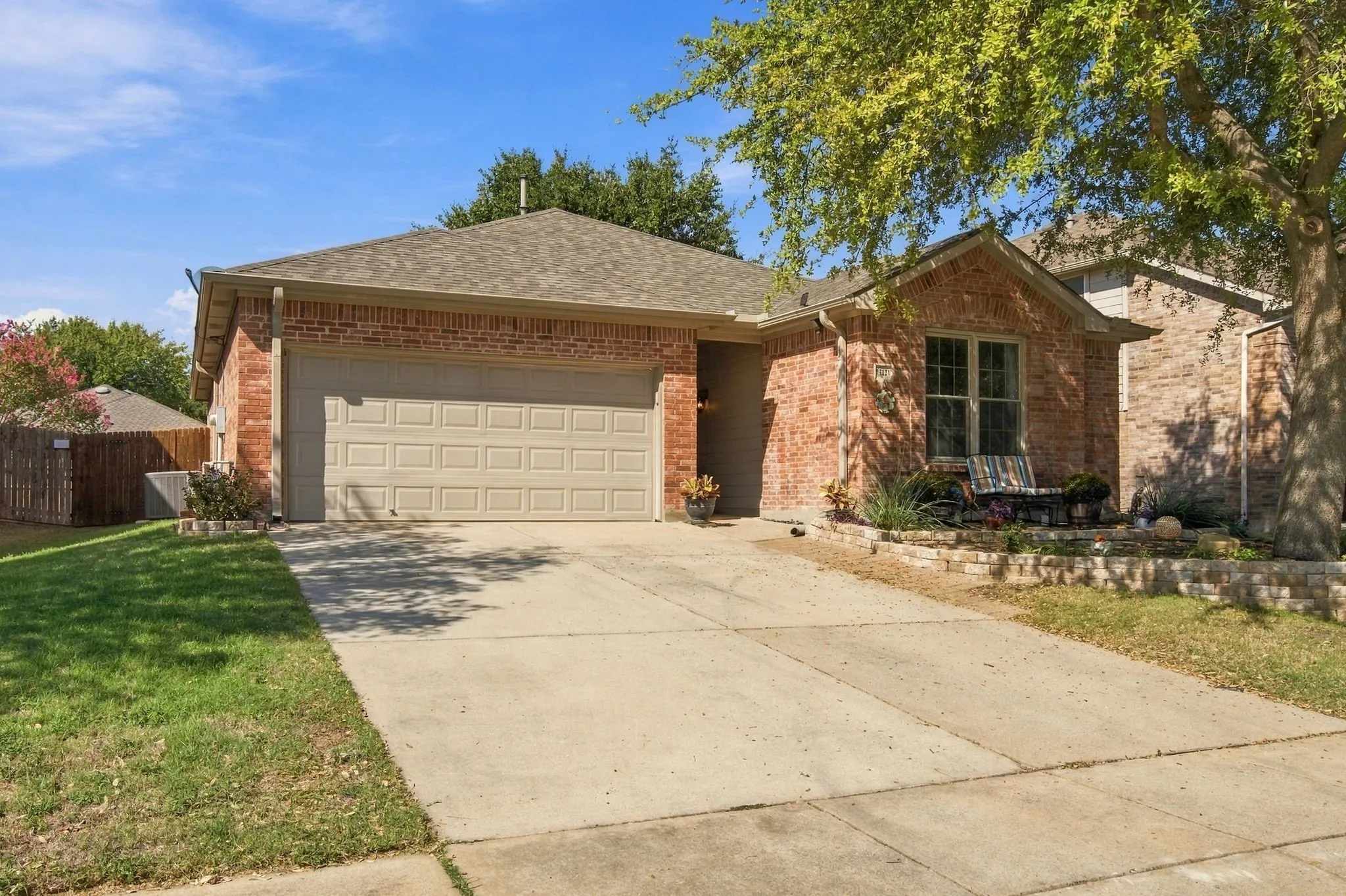 Brick exterior with a concrete driveway, two-car garage, and stone-accented front landscaping