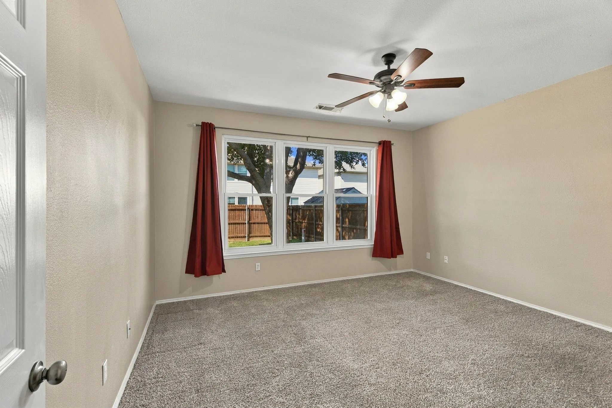 Neutral-toned walls, wall-to-wall carpeting, and a multi-pane window featuring a wooden-blade ceiling fan with an integrated light fixture