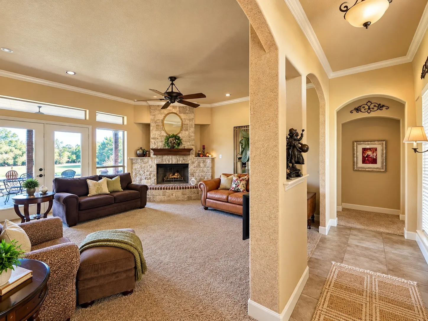 Living area featuring stone-clad fireplace, crown molding, arched room entries, recessed lighting, and dual glass entry doors