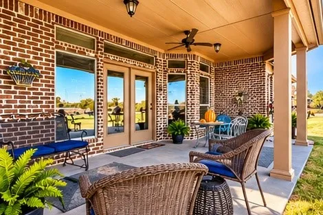 Covered patio featuring red brick masonry, full-light French doors, transom windows, a ceiling fan, and structural support columns