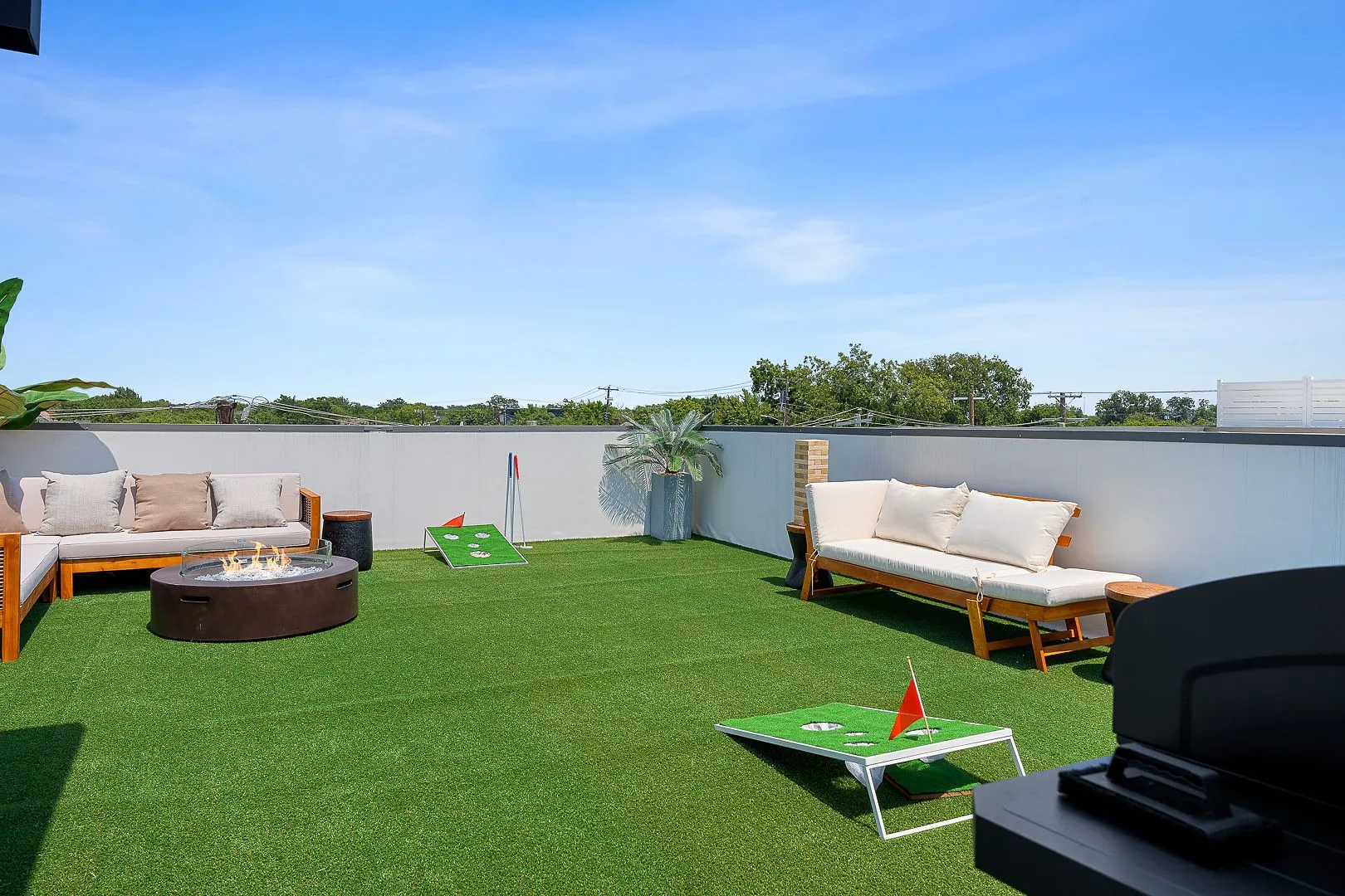 Rooftop terrace featuring synthetic turf, perimeter walls, and a circular fire pit