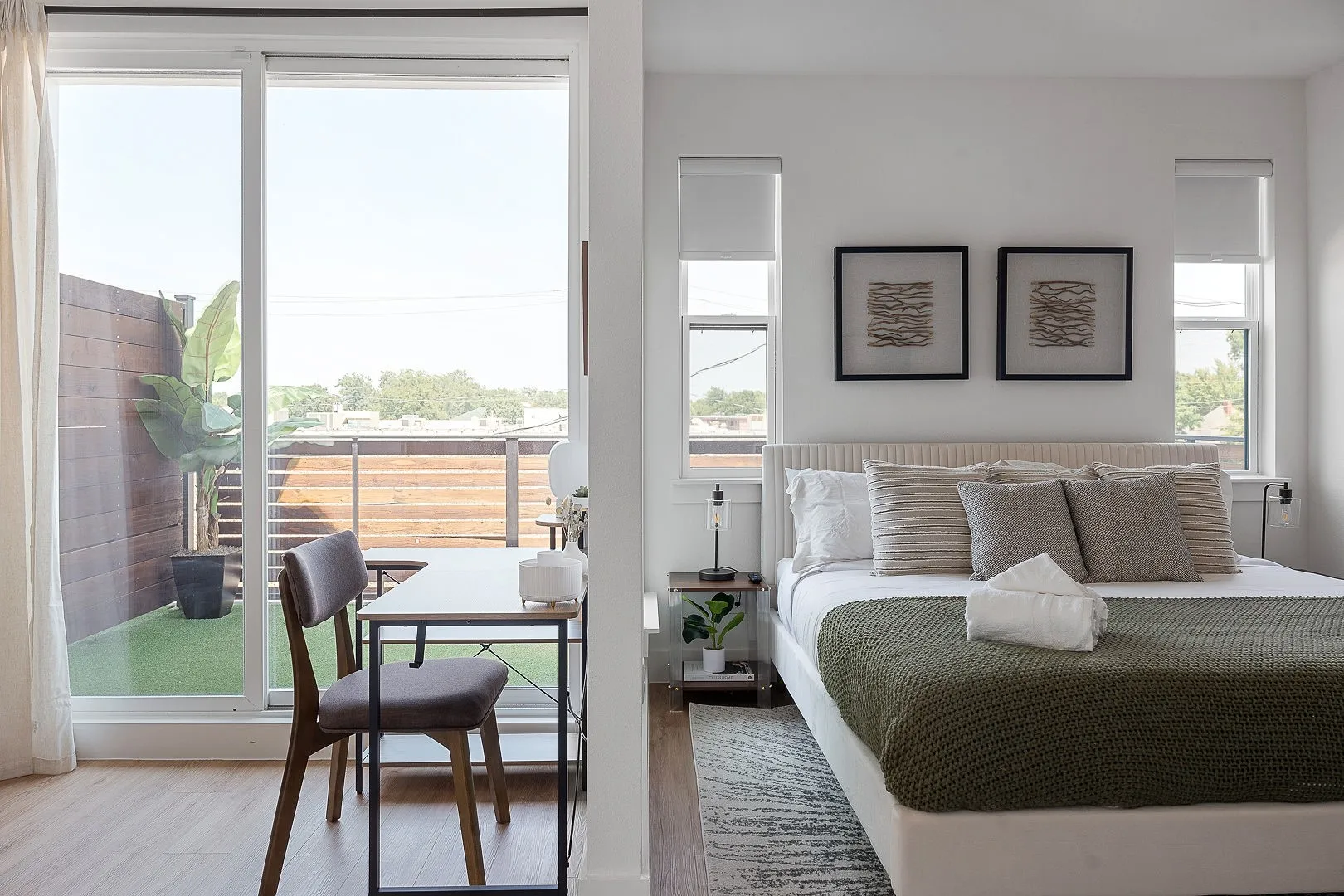 Sliding glass doors opening to a private balcony with horizontal wood slat fencing and artificial turf, complemented by wood-finish flooring and dual double-pane windows