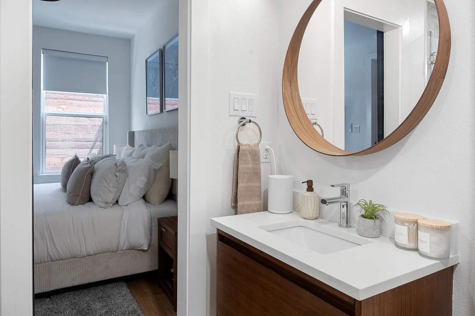Wall-mounted circular wood-finish mirror, vanity with white countertop and integrated sink, and polished chrome faucet