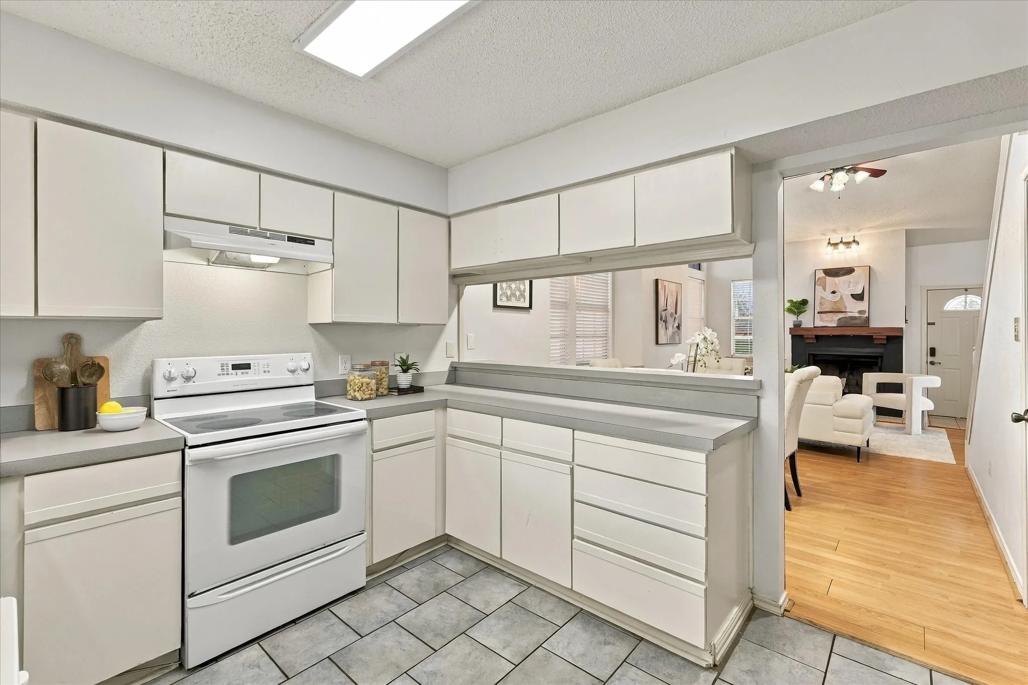 Kitchen featuring white cabinetry, gray solid-surface countertops, tile flooring, and an electric range