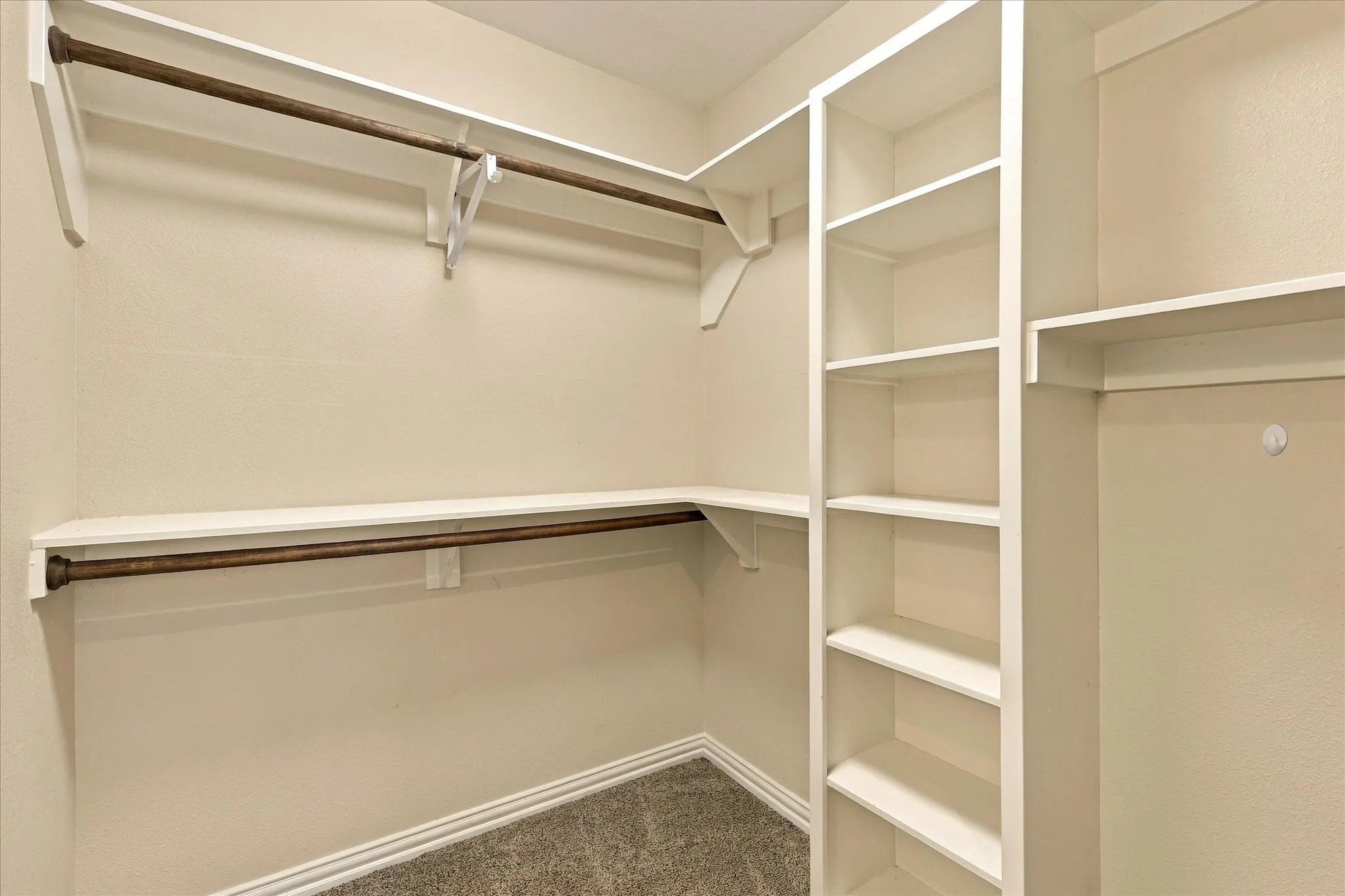 Walk-in closet featuring tiered shelving, built-in vertical storage towers, and multiple integrated hanging rods
