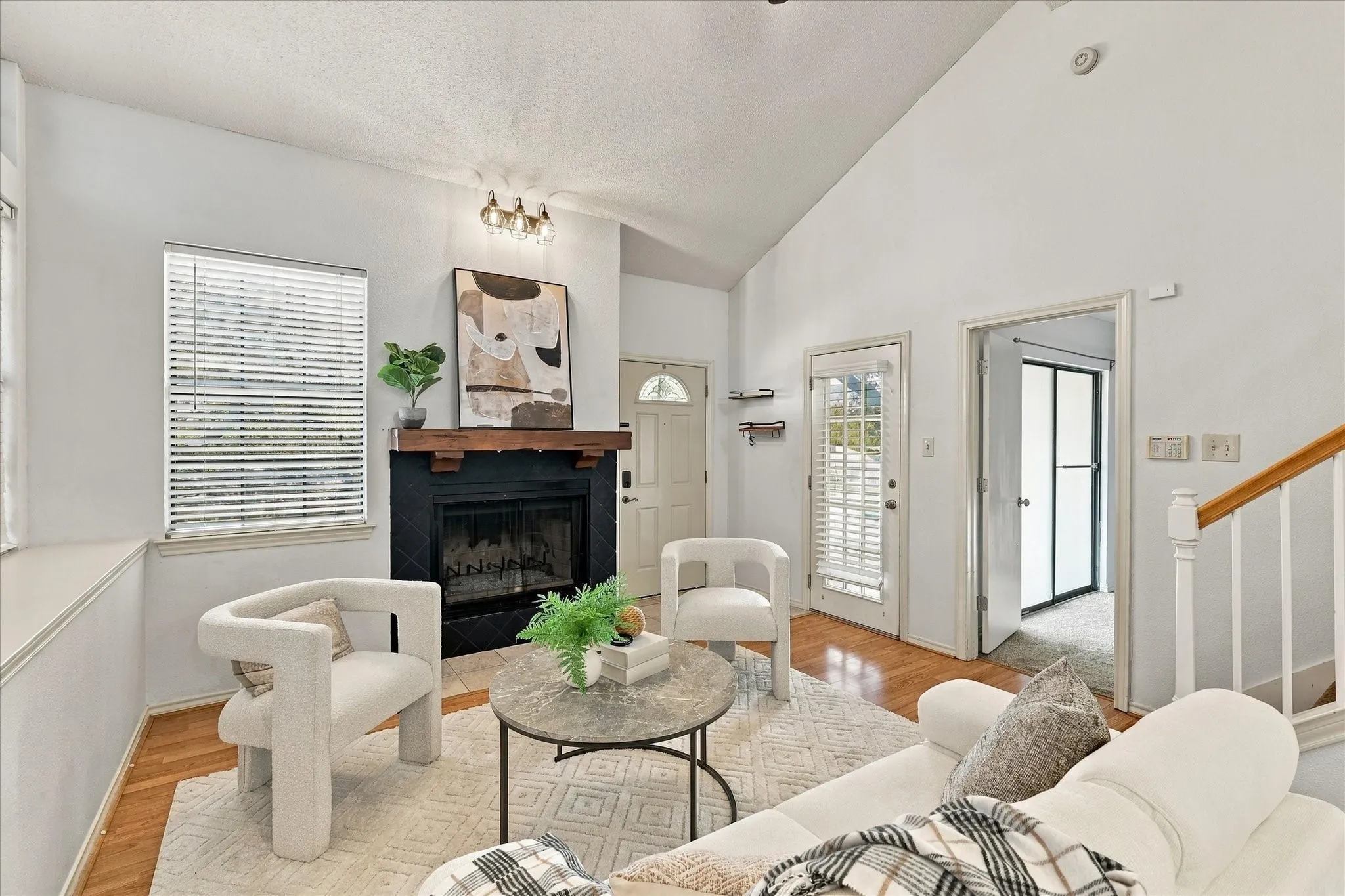Vaulted ceilings, fireplace with black tile surround and wood mantel, wood-finish flooring, and multi-lite exterior doors