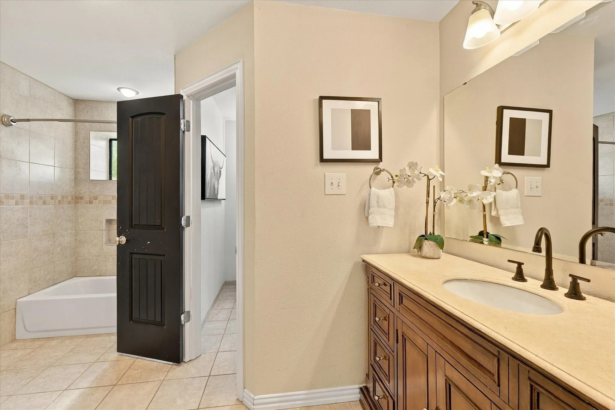 Bathroom featuring a wood vanity with a stone countertop, an integrated oval sink, matte finish plumbing fixtures, and a tiled shower-tub combination