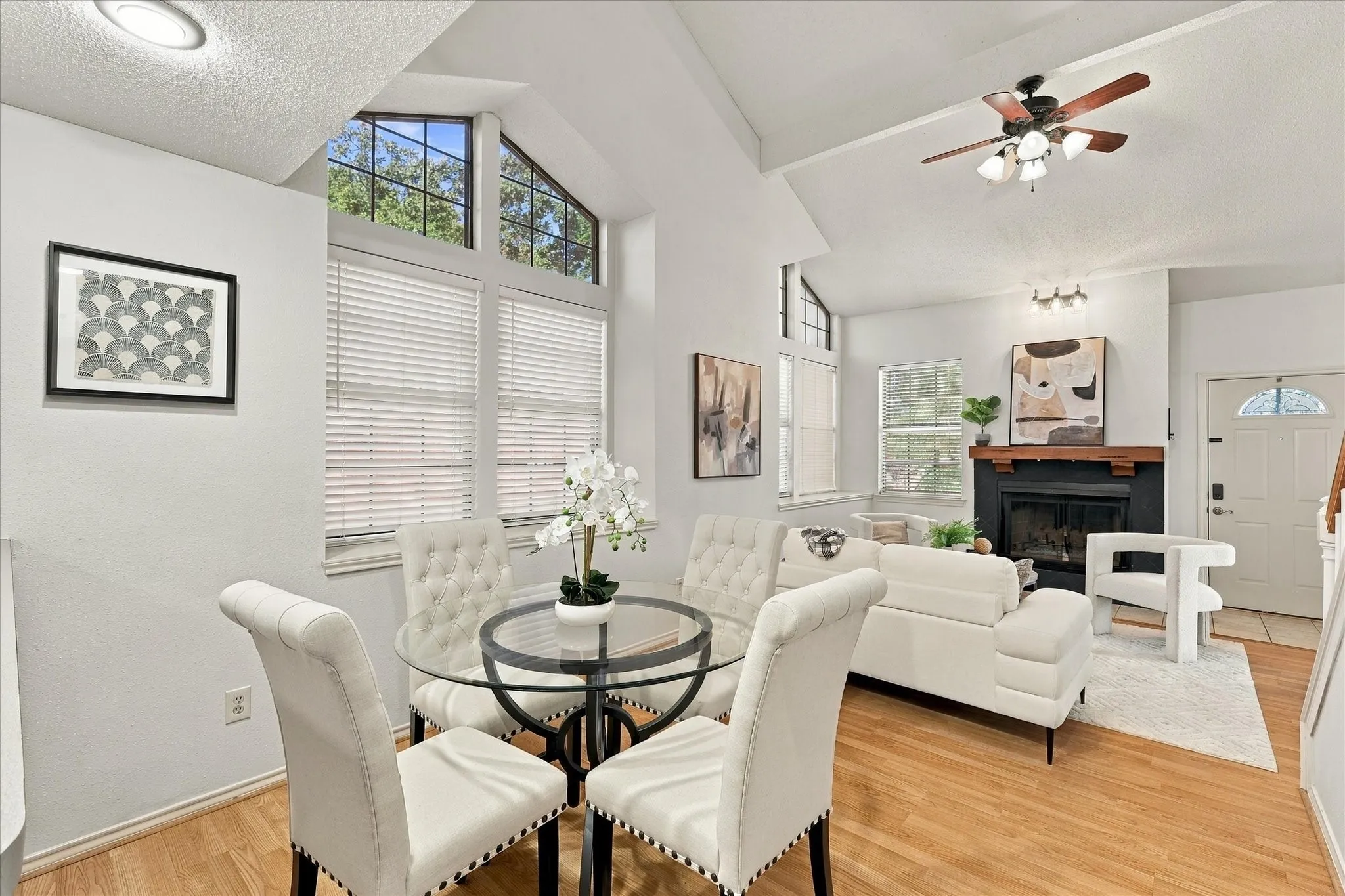 Vaulted ceilings, expansive multi-pane windows, wood-finish flooring, and a fireplace with a wood mantel