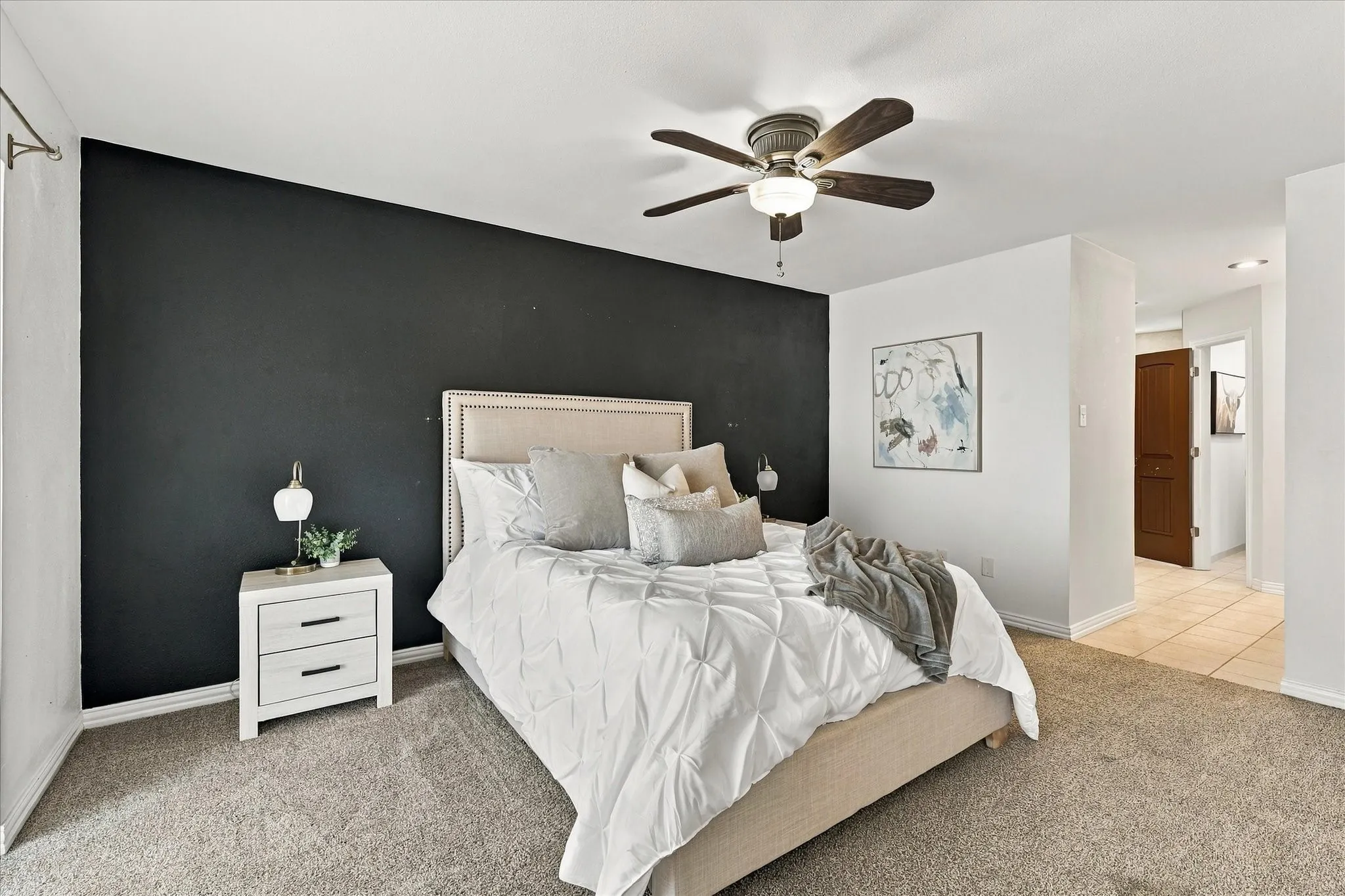 Neutral-toned carpeting, accent wall, and ceiling fan with integrated lighting