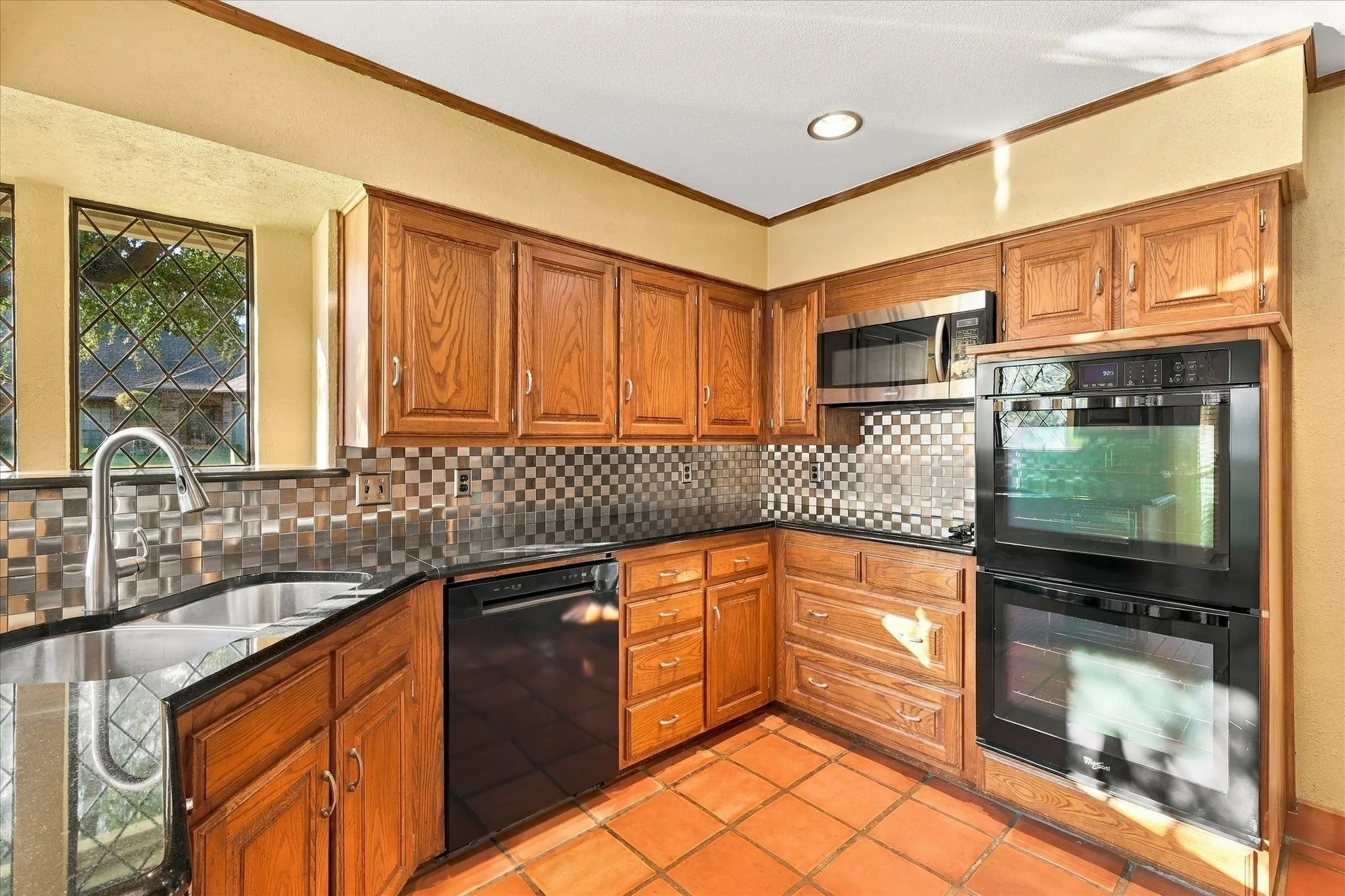 Corner sink beneath windows, with a double oven nearby.