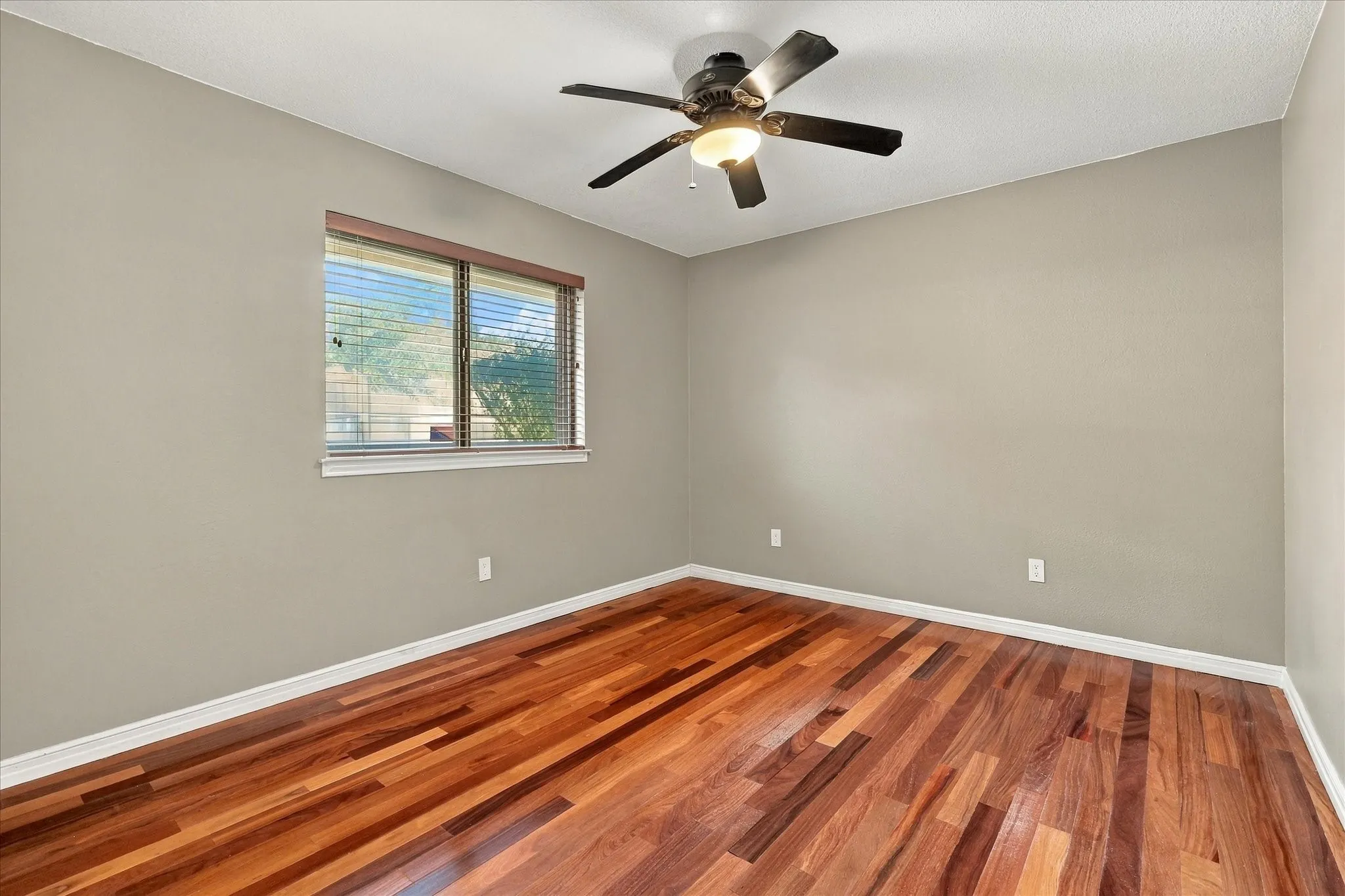  Secondary bedroom with wood flooring and ceiling fan.