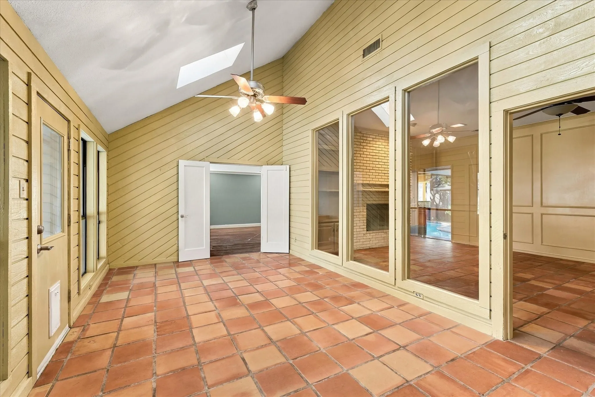 Sunroom with skylights, tall windows and access to the backyard.