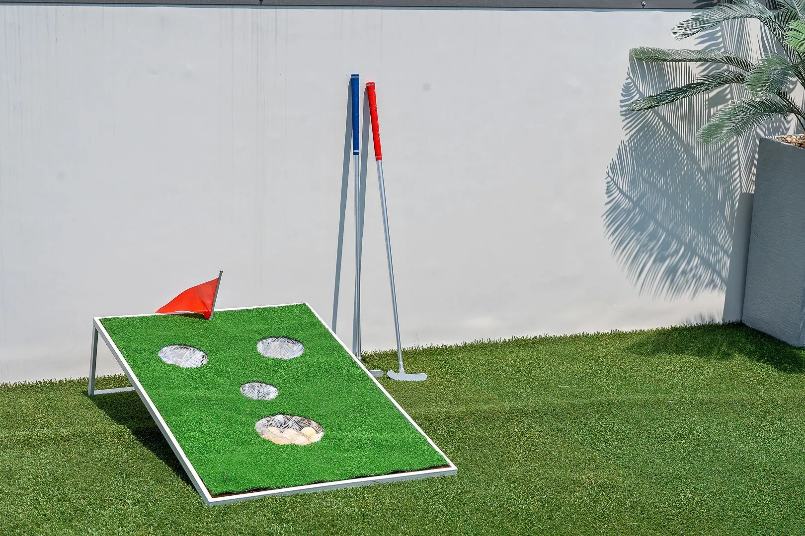 Outdoor space featuring synthetic turf surfacing and a solid wall boundary