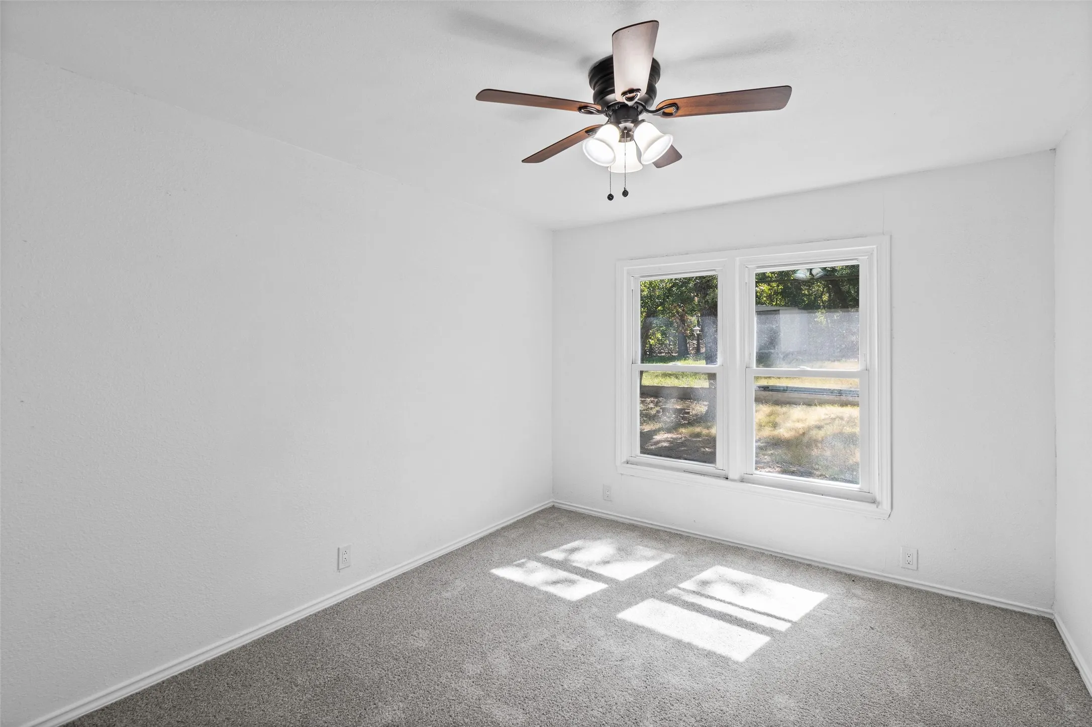 Room featuring neutral wall-to-wall carpeting, white walls, double-pane window, and a ceiling fan with integrated three-light fixture