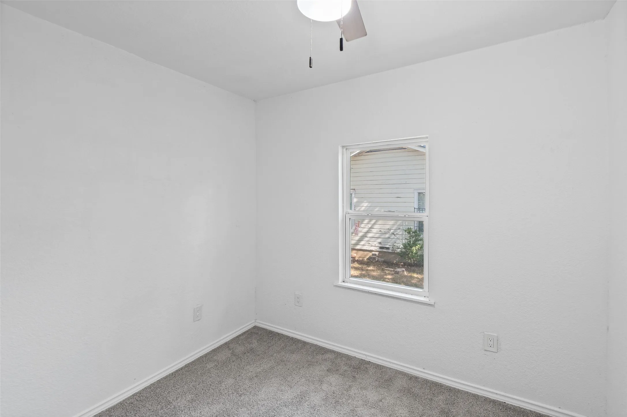 Neutral-toned interior space featuring wall-to-wall carpeting and a ceiling-mounted light fixture with a fan
