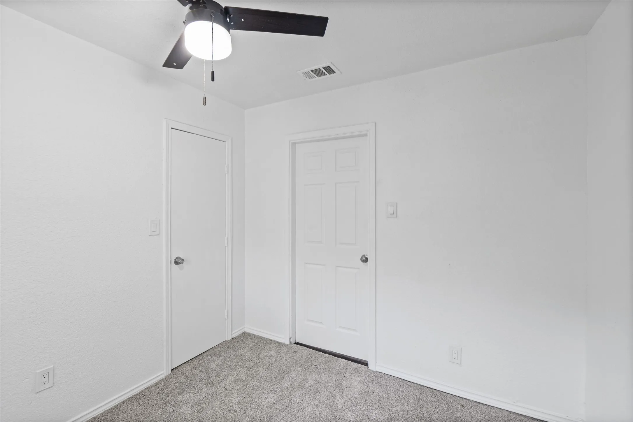 Neutral-toned carpeting, ceiling fan with integrated lighting, six-panel interior door, and solid-core door