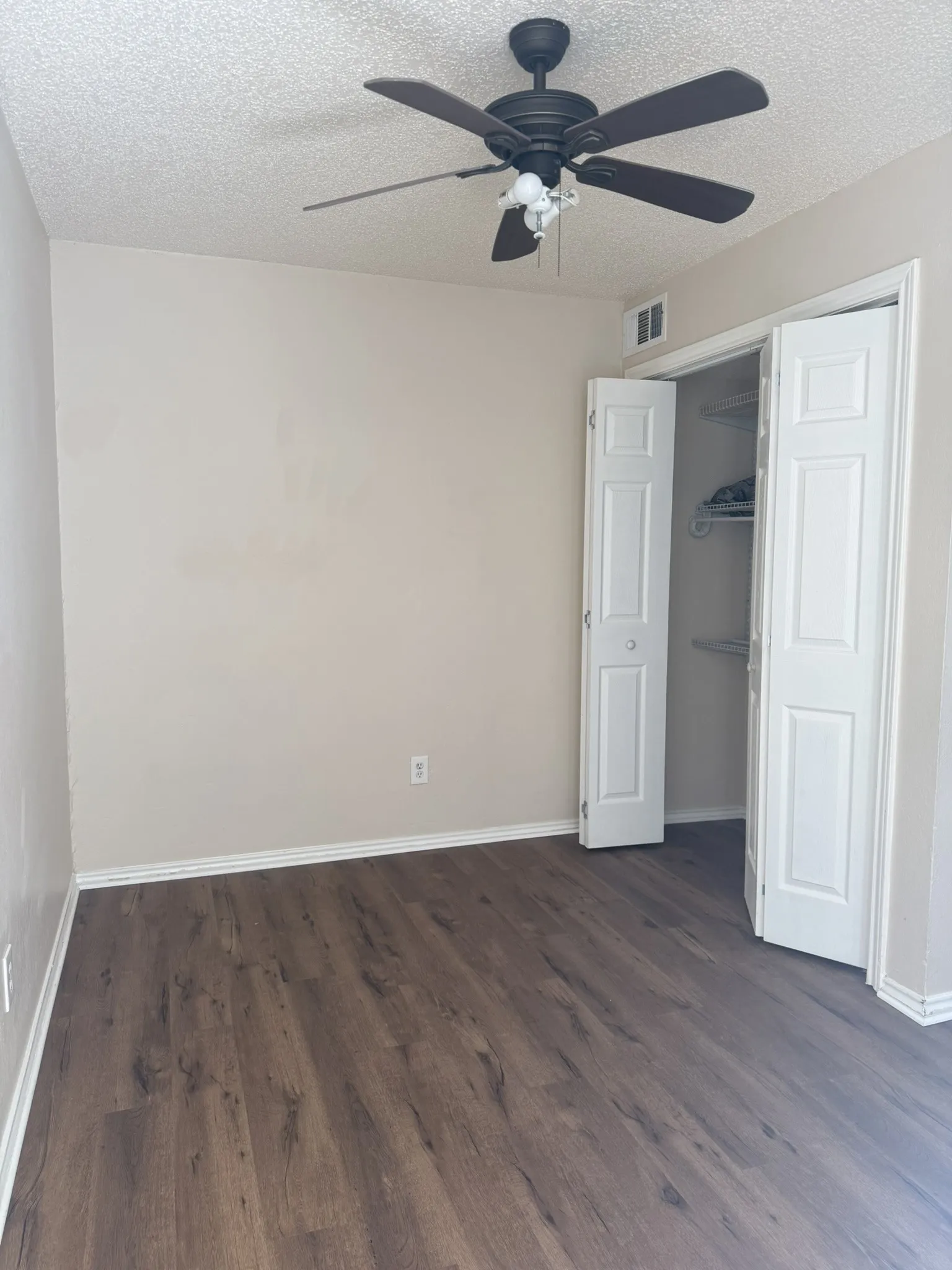Wood-finish flooring, ceiling fan with integrated lighting, and closet with bifold doors and built-in shelving