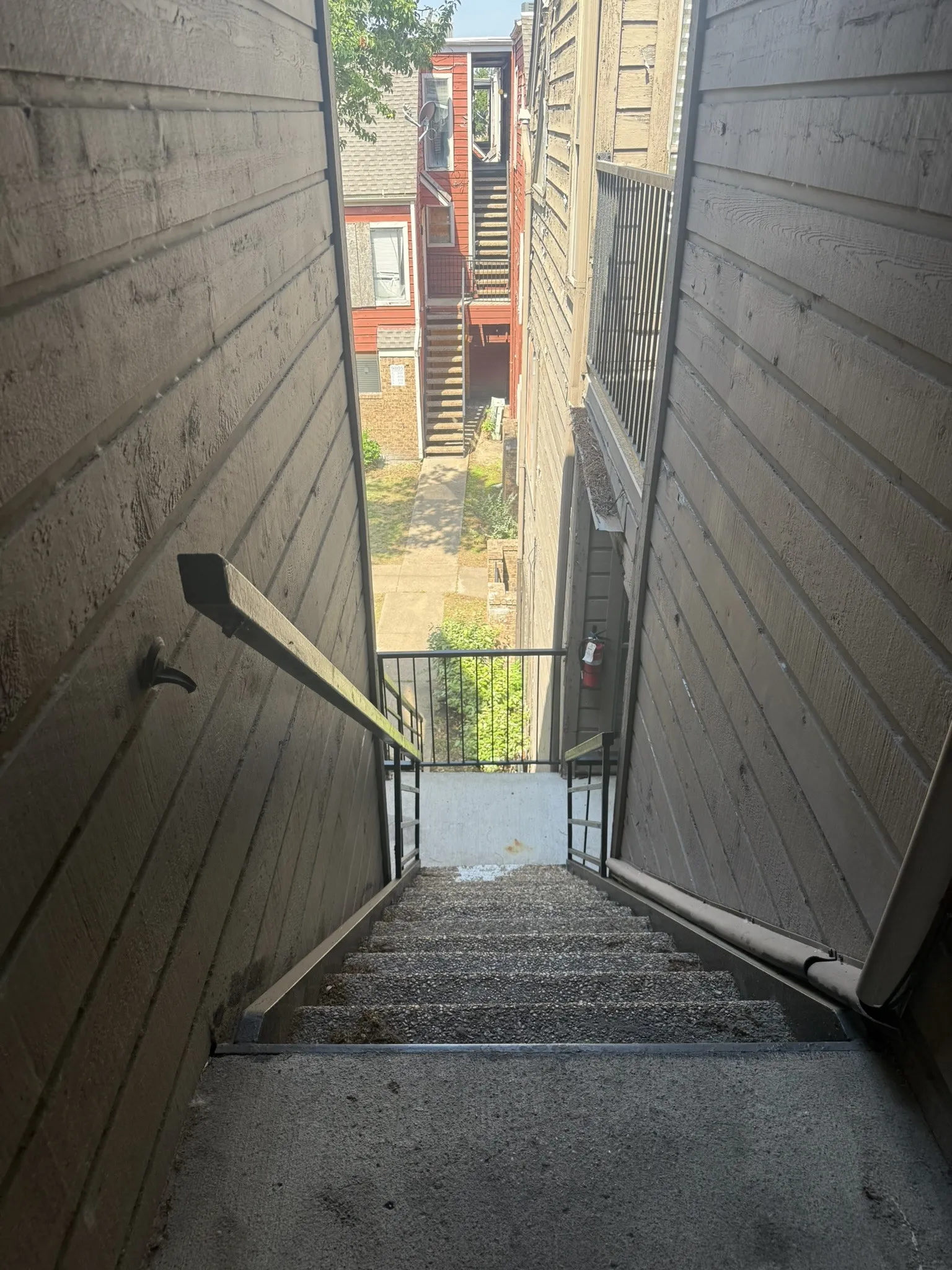 Exterior staircase featuring horizontal siding, metal handrails, and exposed aggregate concrete steps