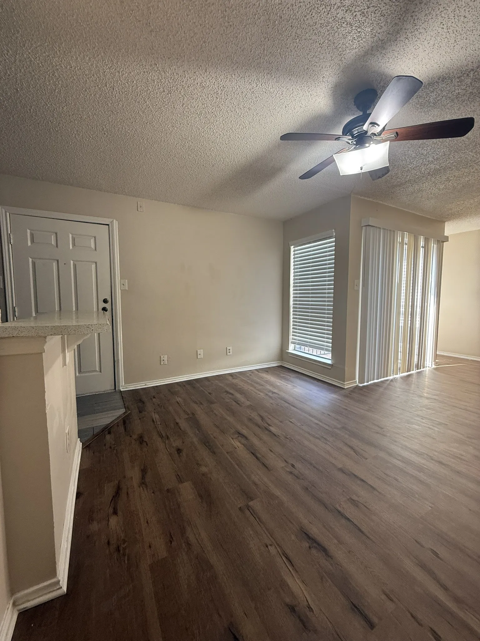 Wood-finish flooring, ceiling fan with integrated light fixture, and vertical blinds
