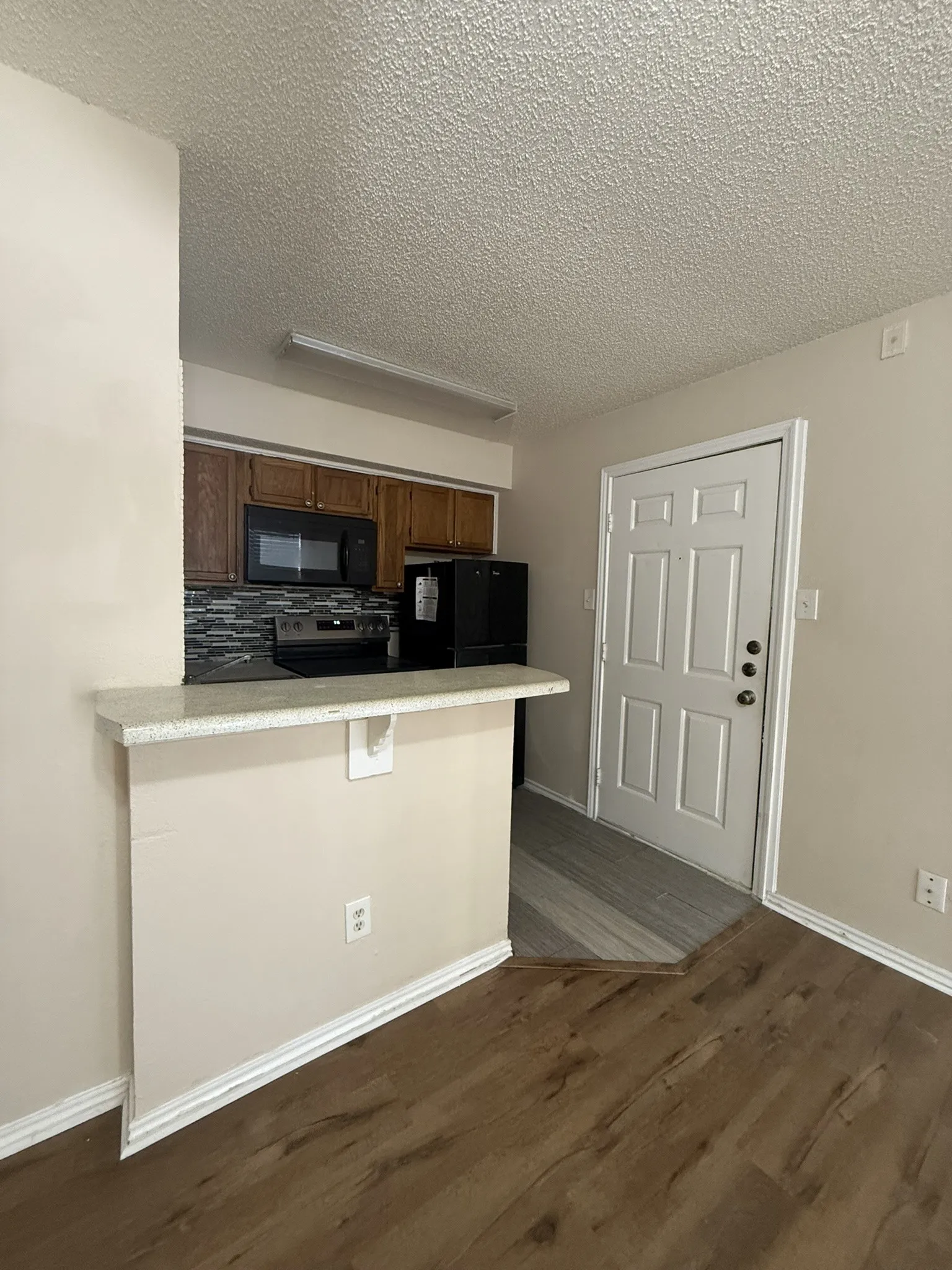 Kitchen featuring a breakfast bar with stone-finish countertop, wood-finish cabinetry, mosaic tile backsplash, and built-in microwave