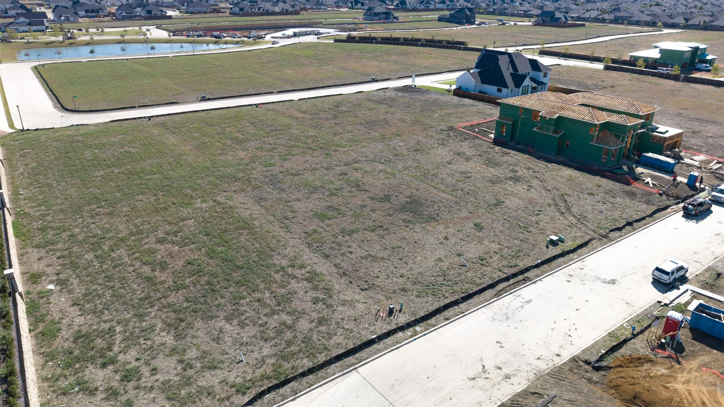 Expansive vacant residential lot featuring cleared land, established curb infrastructure, and paved street access