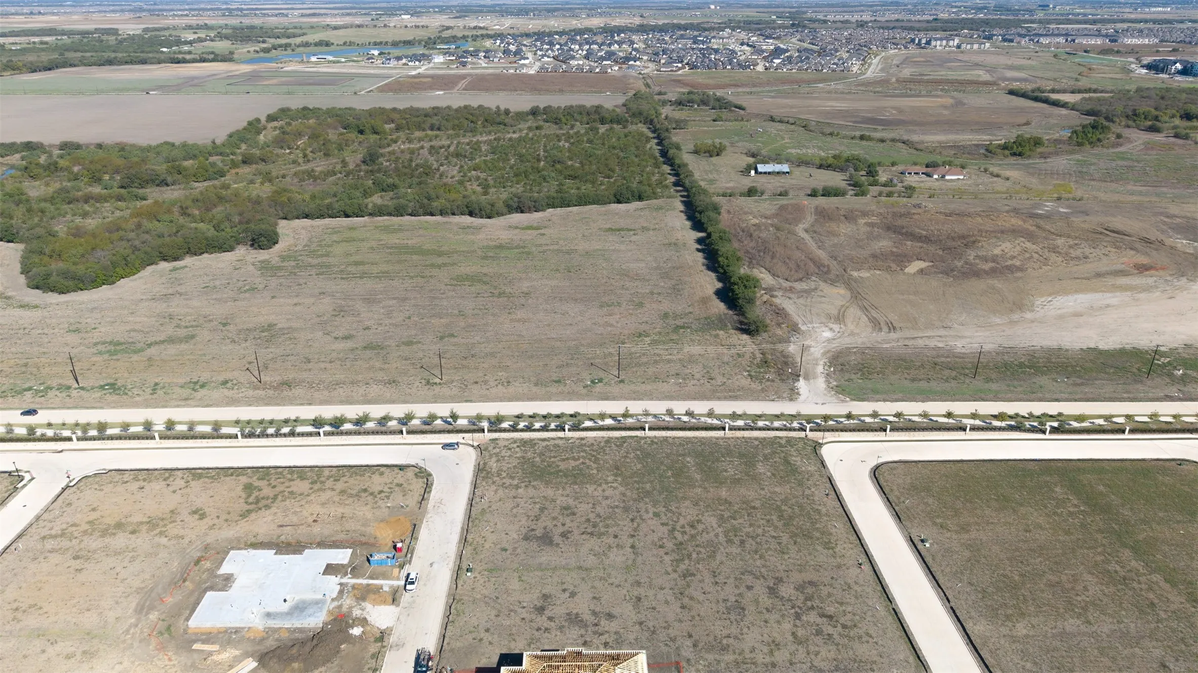 Expansive undeveloped land parcel featuring cleared terrain, mature tree lines, and proximity to paved roadway infrastructure