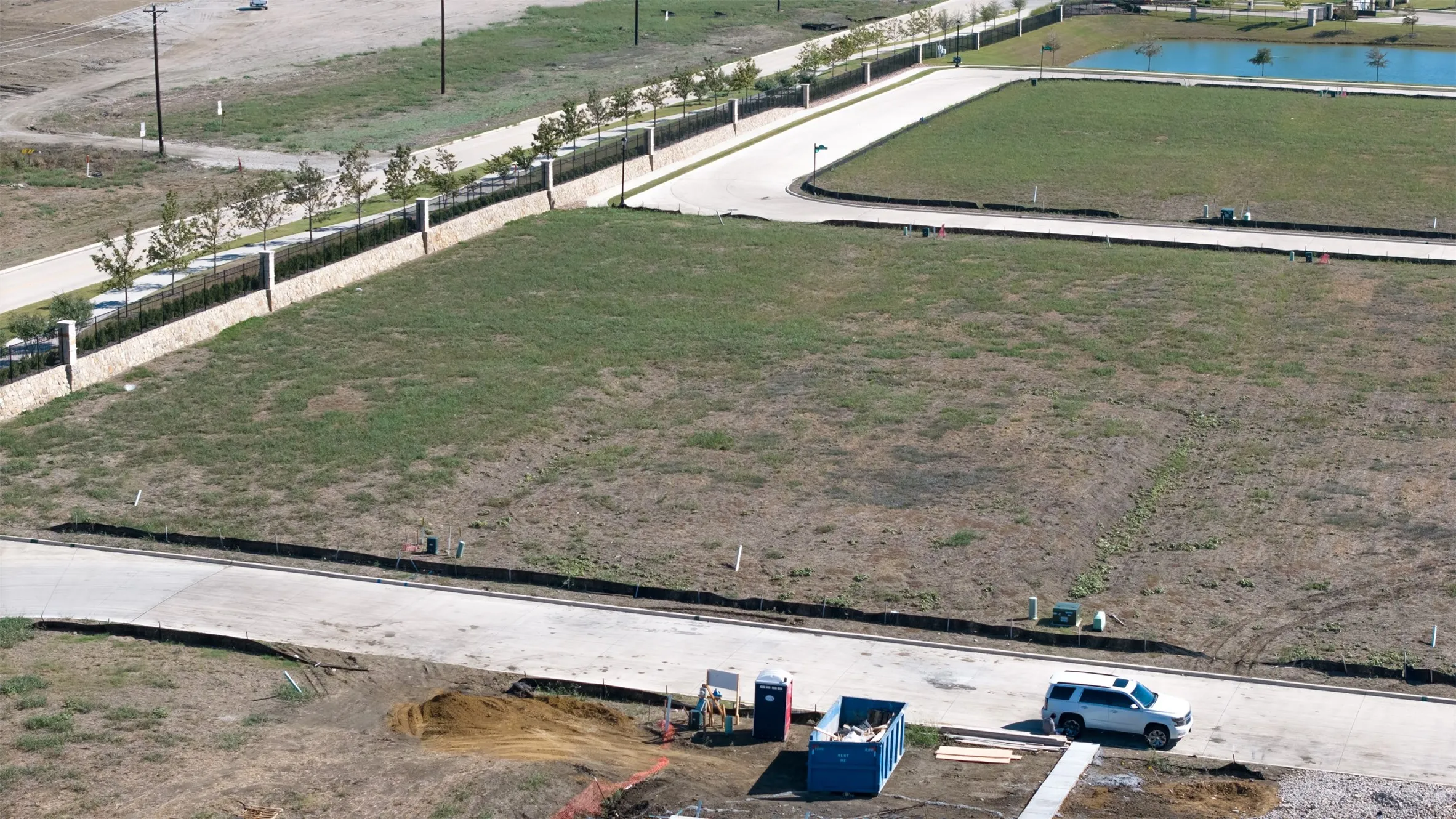 Vacant corner lot featuring paved street access, concrete curbing, and perimeter masonry fencing