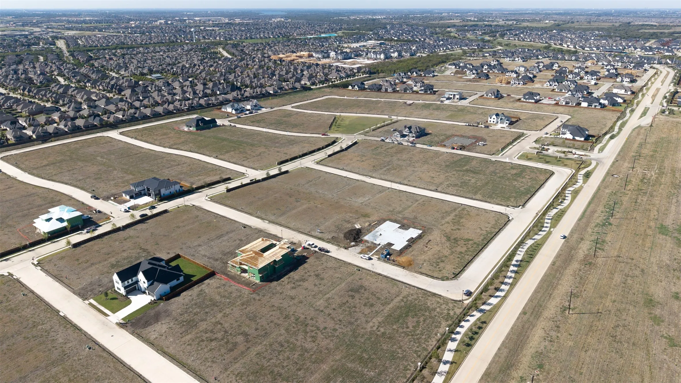 Aerial perspective of master-planned development featuring paved roadways, concrete sidewalks, and subdivided residential lots