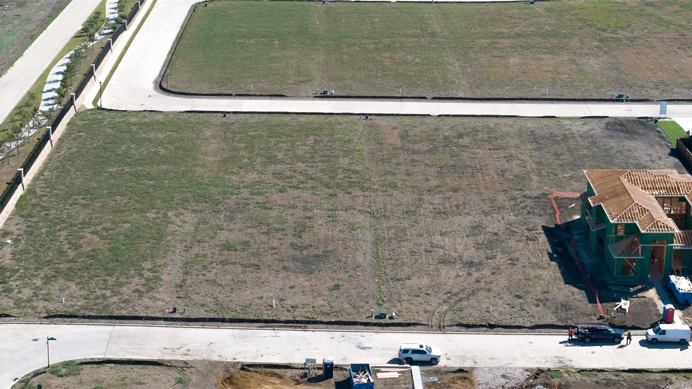 Expansive vacant lot featuring a cleared building envelope, paved street access, and perimeter fencing