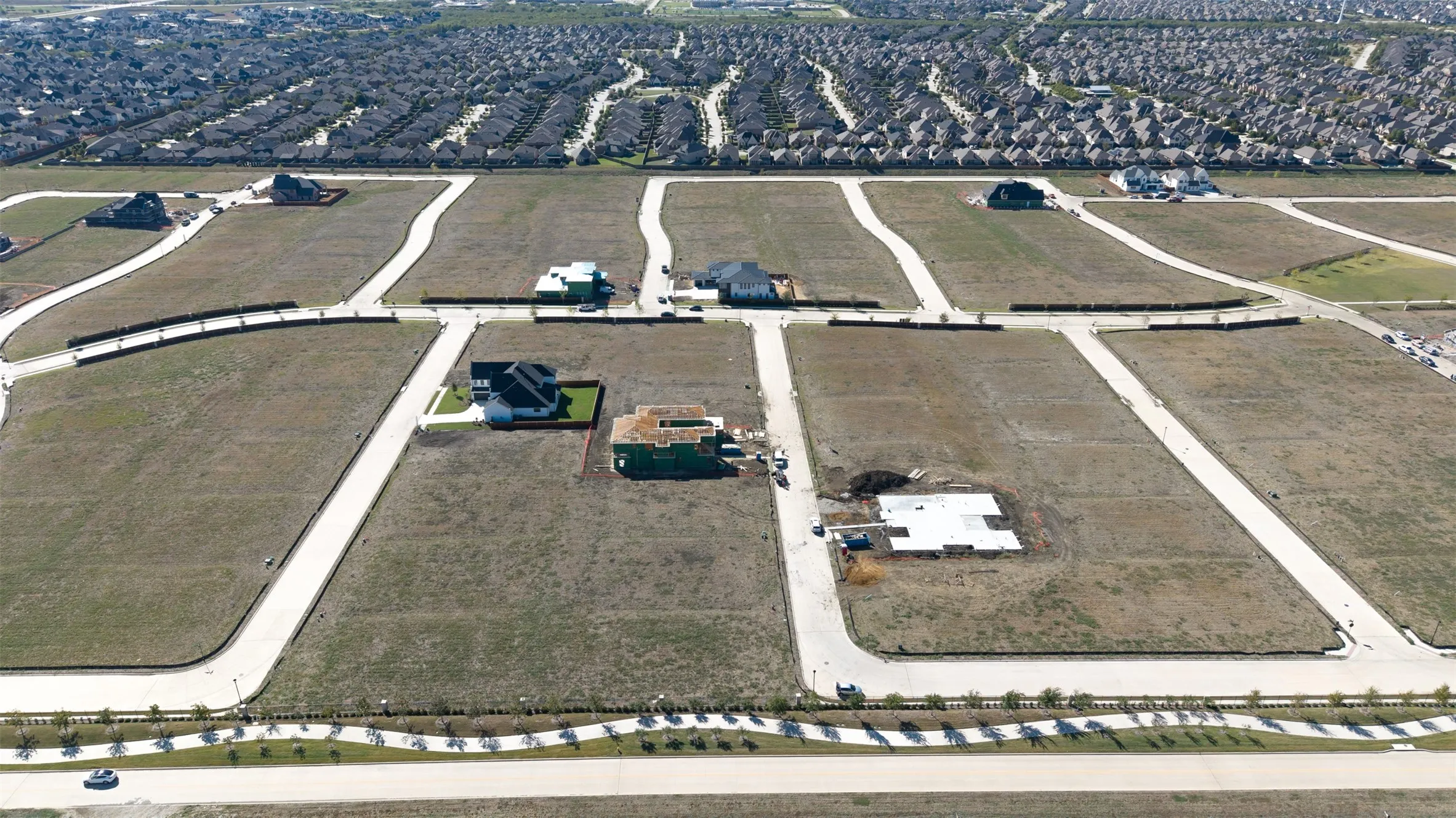 Aerial view of a residential development featuring expansive land parcels, paved road infrastructure, and established utility connections
