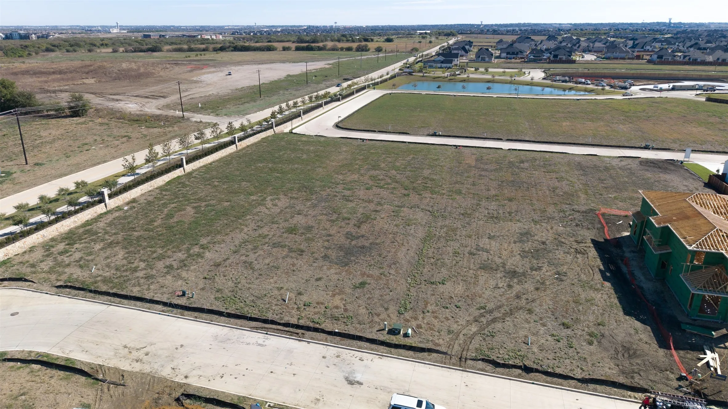 Expansive residential lot featuring concrete street access, perimeter curbing, and proximity to a neighborhood pond