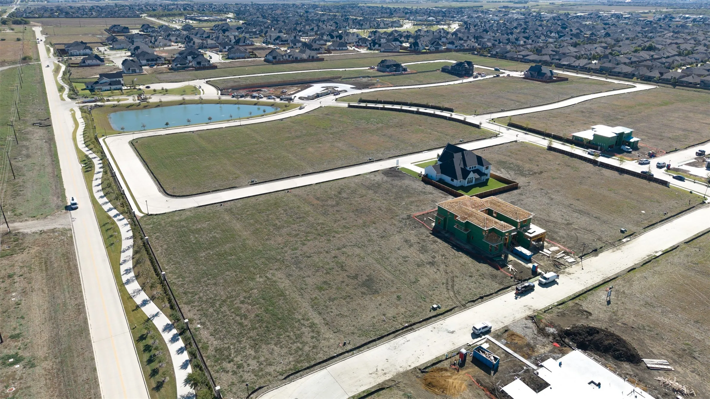 Expansive residential lot featuring concrete street infrastructure, curbing, and proximity to a community pond