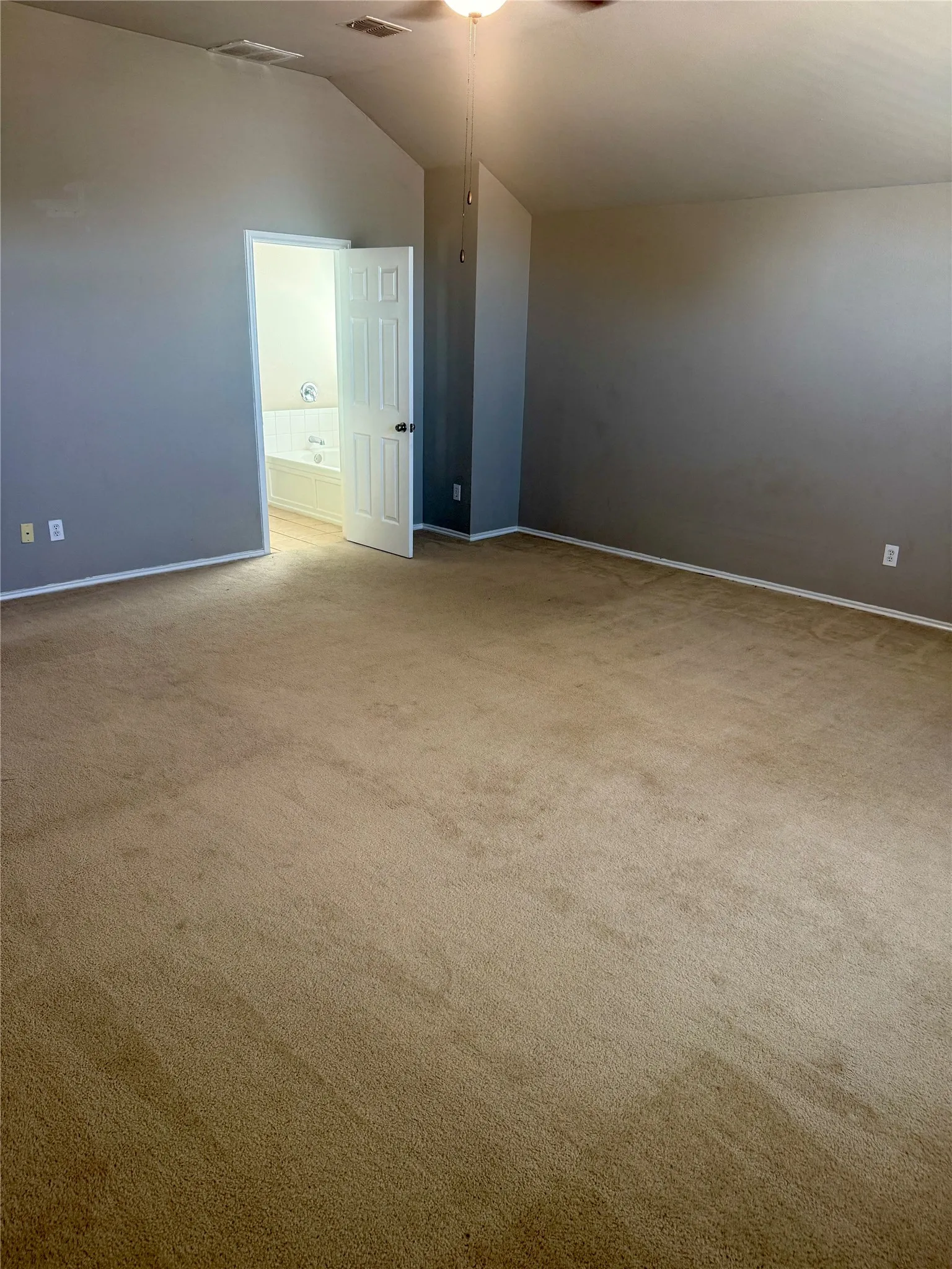 Vaulted ceiling featuring a central ceiling fan, neutral wall paint, and wall-to-wall carpeting