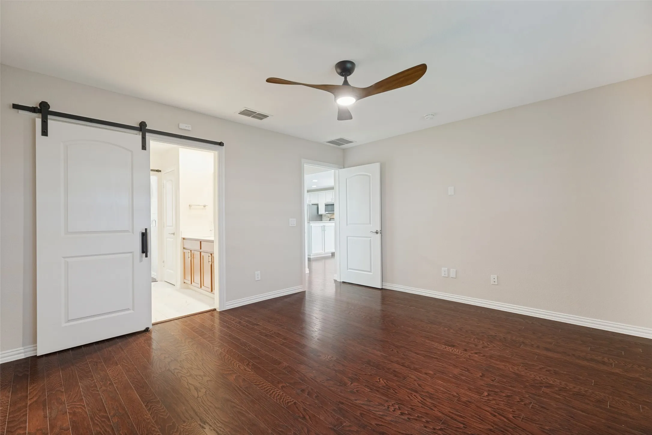 PRIMARY BEDROOM IS LARGE WITH SLIDING BARN DOOR, CEILING FAN, PLANTATION SHUTTERS