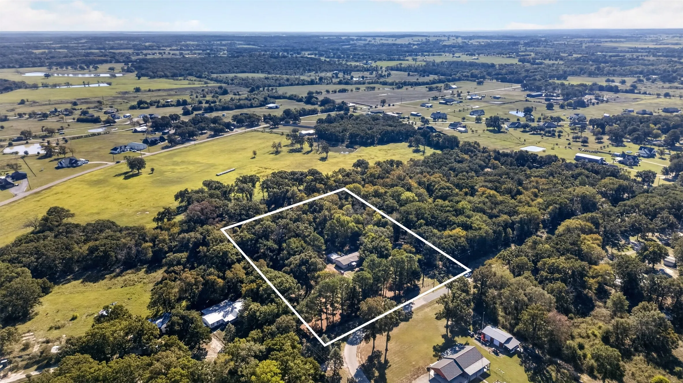 Aerial perspective of a sprawling parcel featuring dense tree coverage, established perimeter boundaries, and expansive natural landscape