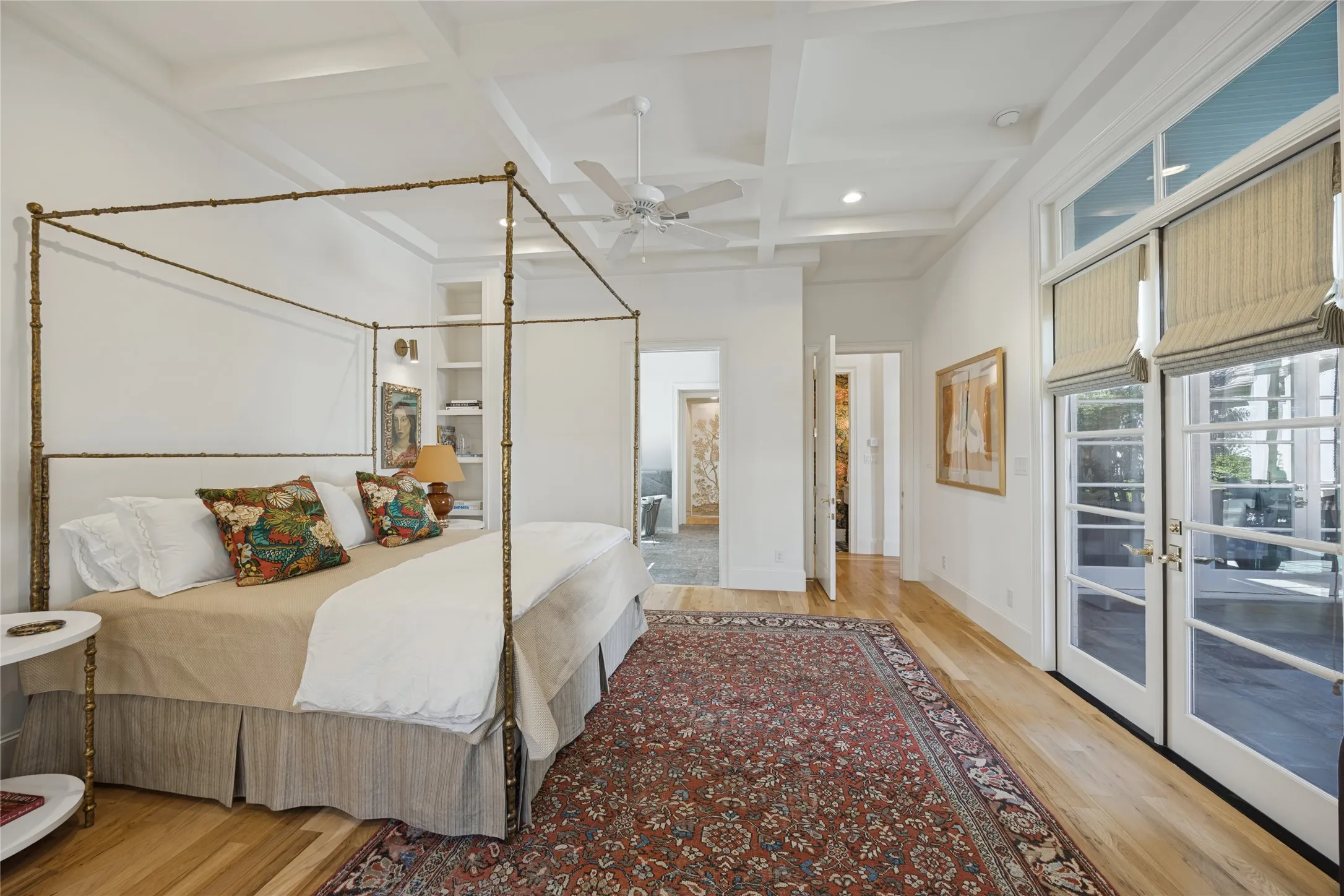 Coffered ceiling, wood-finish flooring, built-in shelving, and double glass-paneled doors with transoms