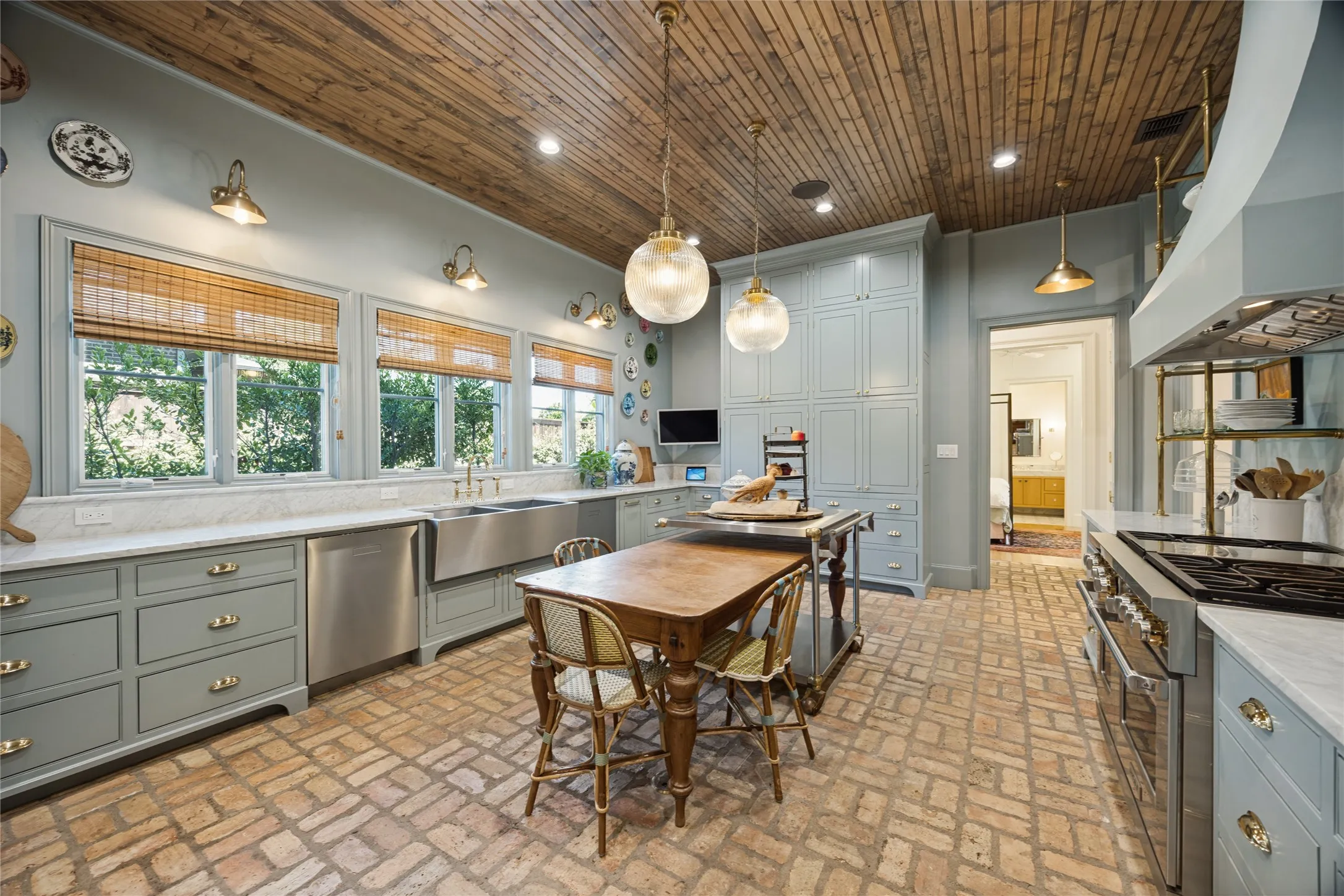 Kitchen featuring tongue-and-groove wood ceiling, brick flooring, custom cabinetry, professional-grade range, and stone countertops with a farmhouse-style sink