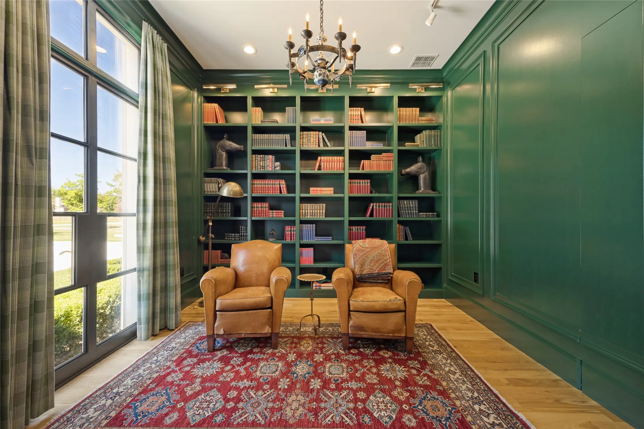Custom floor-to-ceiling built-in cabinetry with integrated accent lighting, expansive metal-framed glass doors, wood-finish flooring, and crown molding