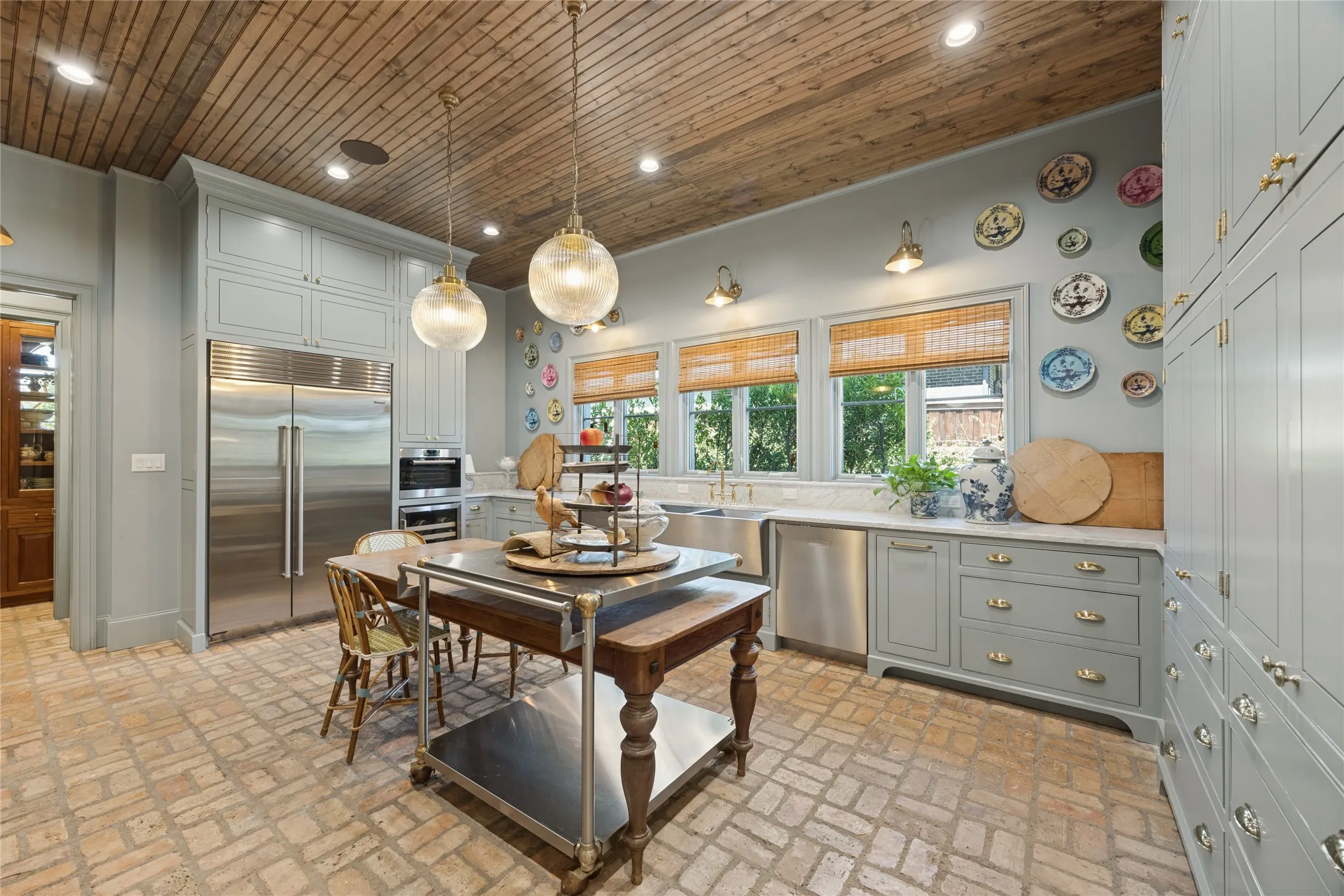 Kitchen featuring a wood-plank ceiling, brick flooring, floor-to-ceiling cabinetry, stainless steel appliances, and dual pendant lighting