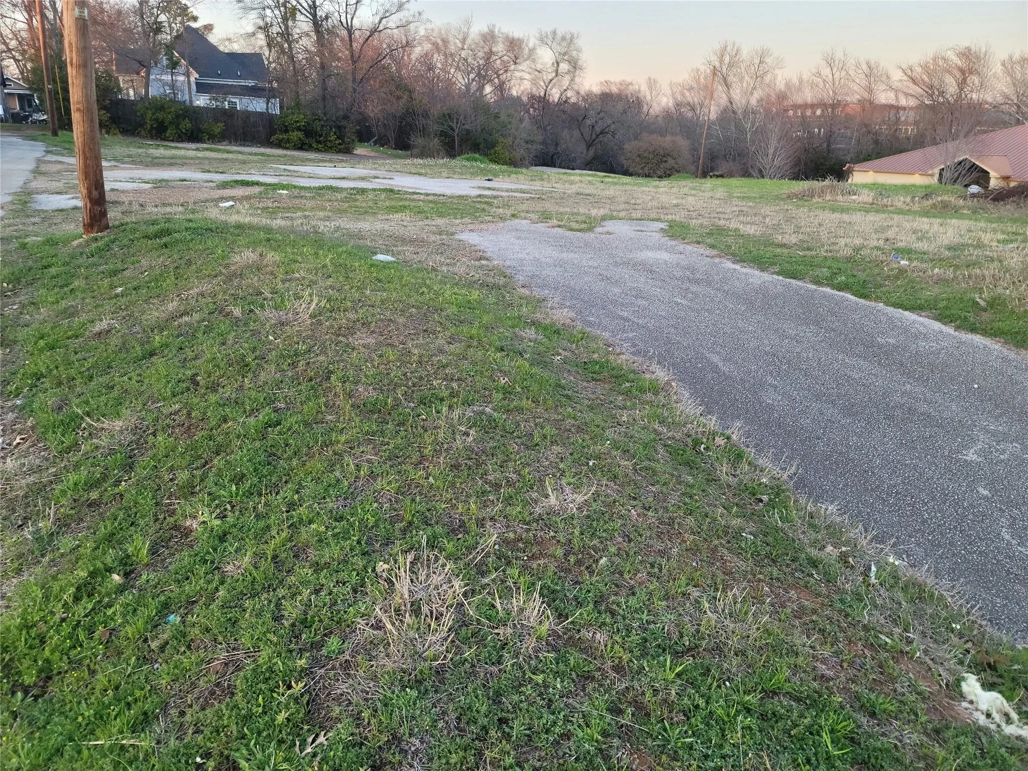 Cleared parcel of land featuring an asphalt driveway and grass lawn