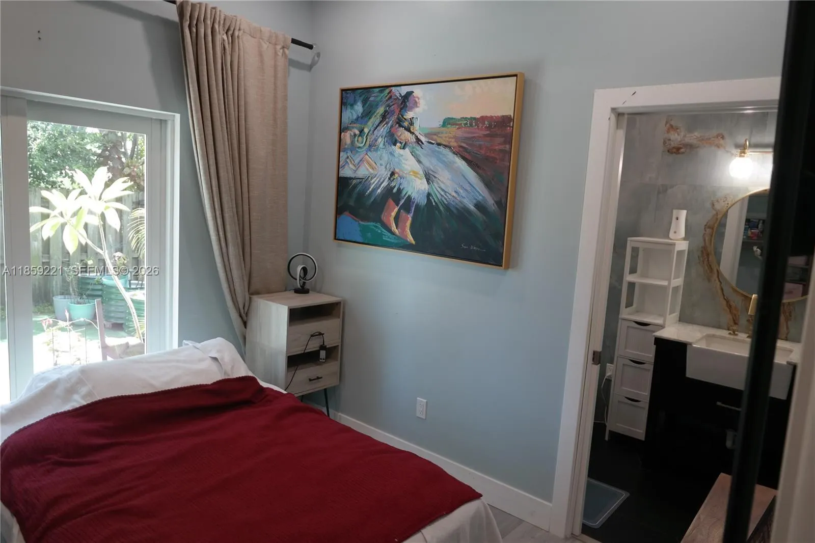 Bedroom with sliding doors for direct access to the back patio and a stunning private bathroom clad in striking sky-blue design.