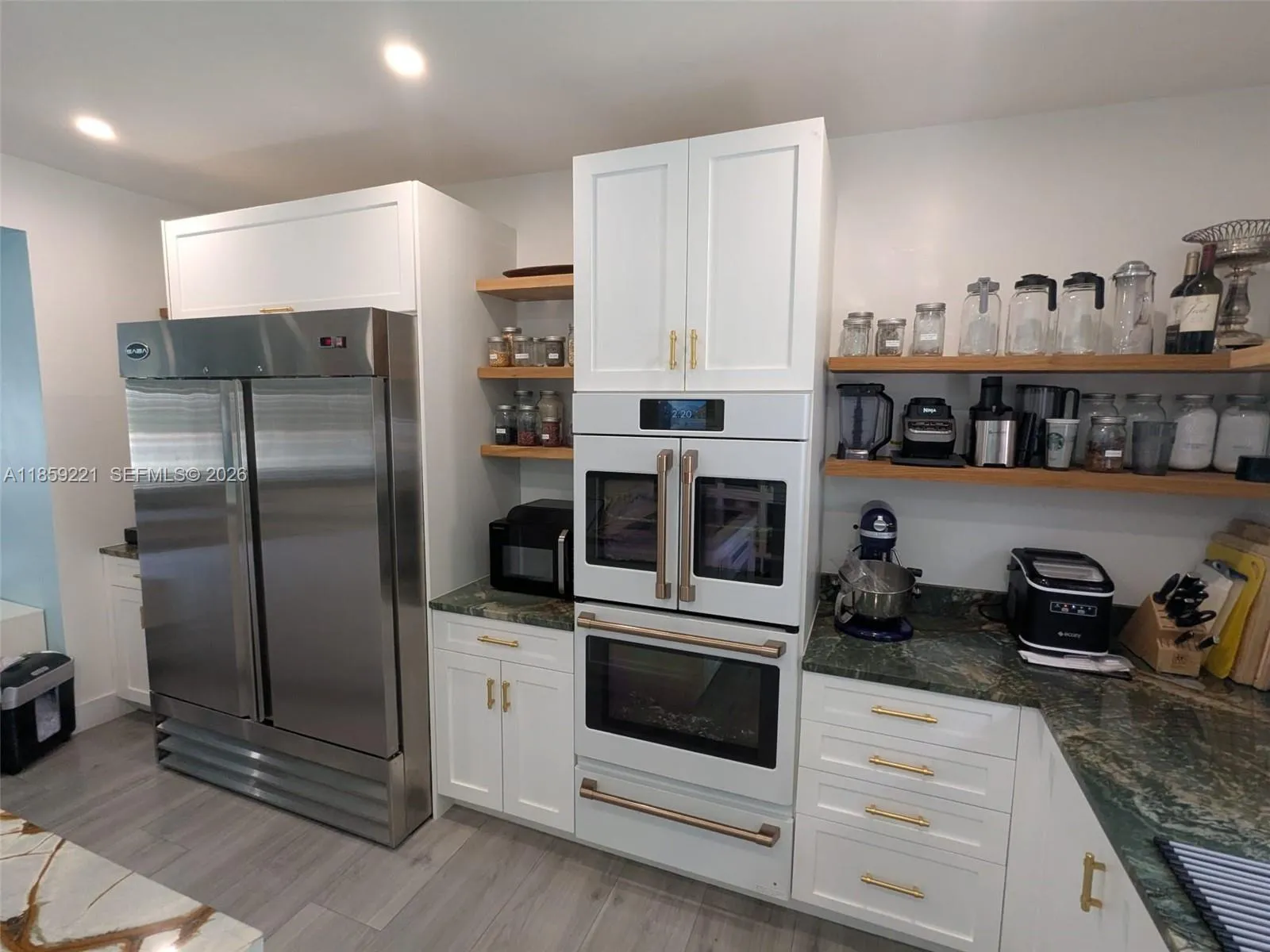 Charming kitchen and oversized Saba double-door stainless steel fridge with warm, coordinated lighting that creates a cozy atmosphere.