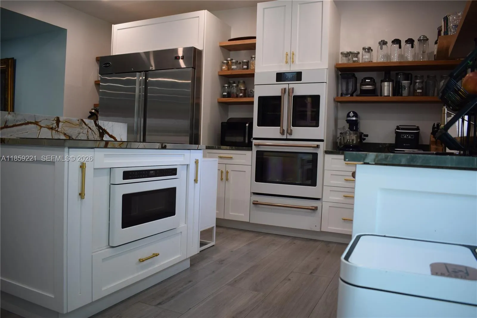 All-white appliances perfectly complement the cabinetry, while elegant golden hardware enhances their beauty.