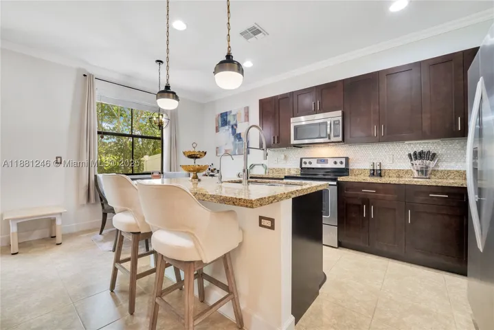 Modern kitchen with granite counters, stainless steel appliances, and rich wood cabinetry. Bright breakfast nook by the window offers a cozy dining space with natural light.