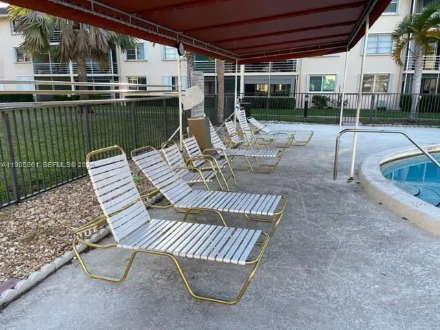 Large heated oval-shaped pool with lounge chairs in a gated area